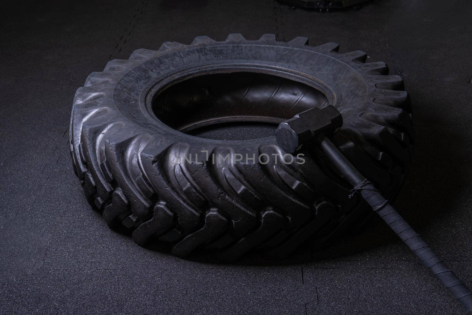 A tire on a black background with a sledgehammer lies for crosfit fitness wheel sledgehammer workout black sport, In the afternoon athlete gym for lifestyle concentration physical, big club. Sweat indoors up, by 89167702191