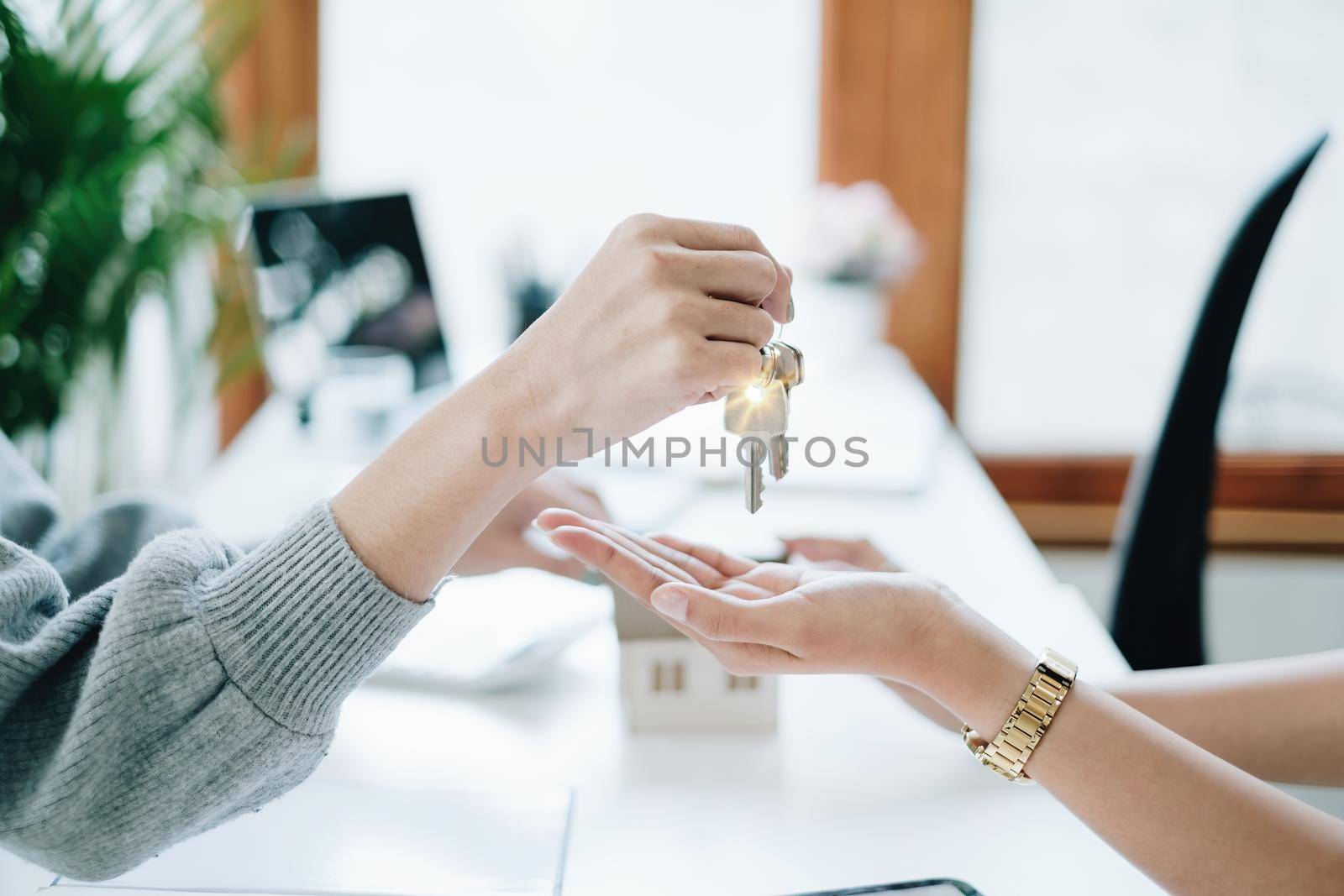 Close up of Business woman giving house key after signing agreement for buying house. Bank manager and real estate concept.
