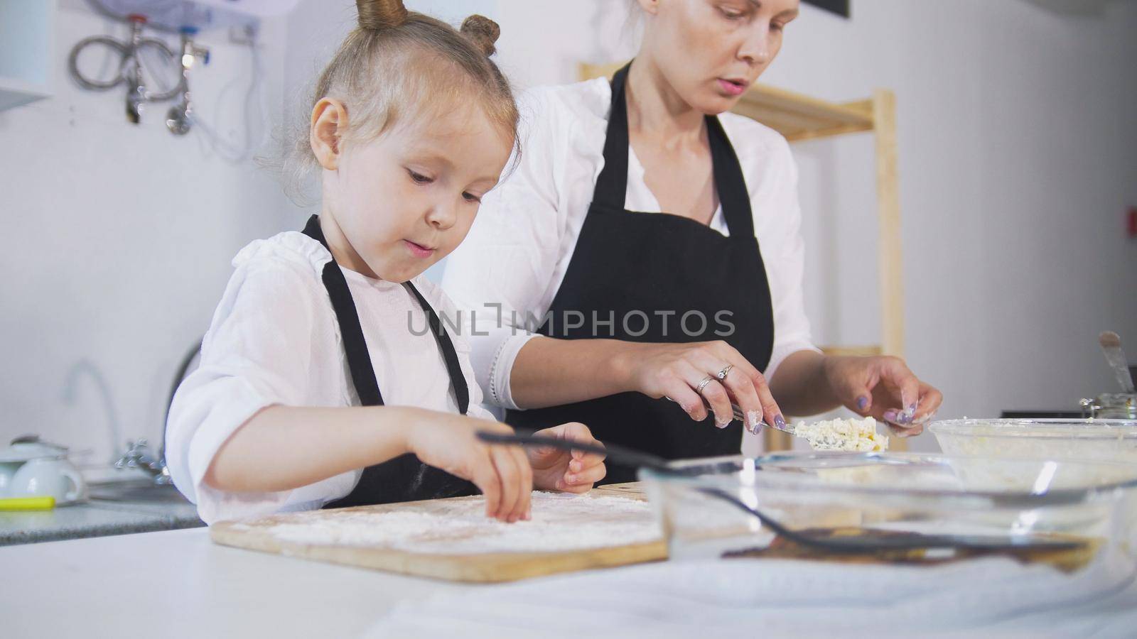 Mother and her little daughter forms cottage cheese pancakes, close up