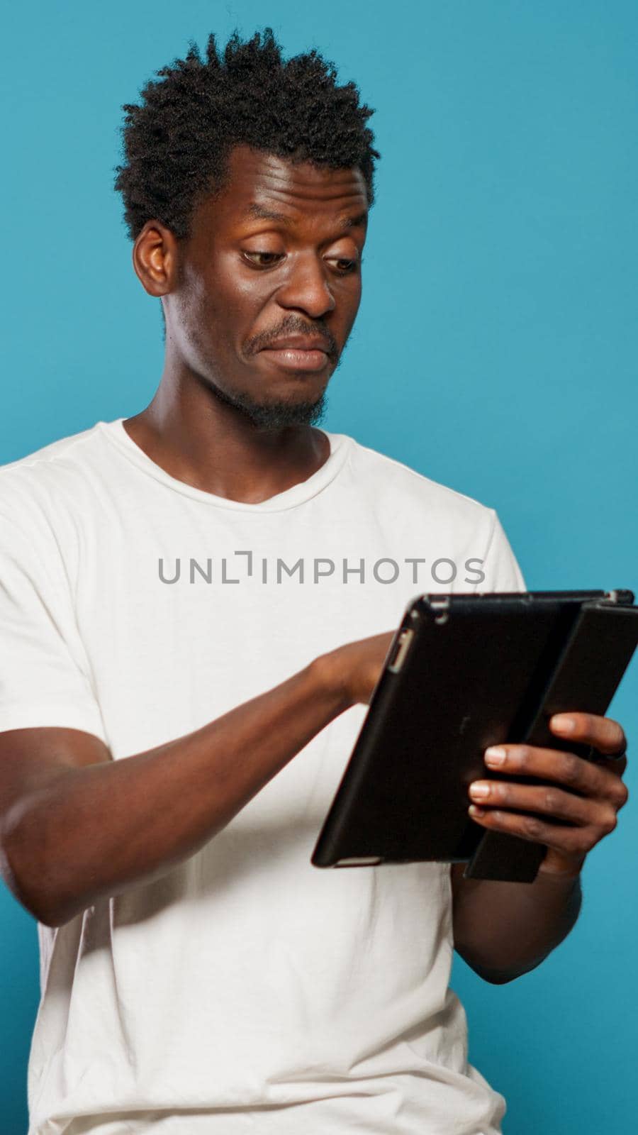 African american man using digital tablet and smiling while typing on touchscreen. Black person with modern device for text messages and communication using technology and laughing