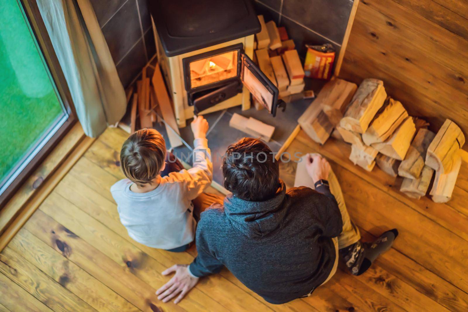 Dad and son spend time by the fireplace in Glamping. Rest in the mountains in Glamping. Cozy fireplace in a mountain house by galitskaya