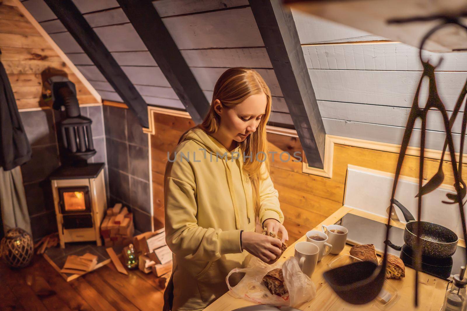 Young woman cooking food whilst glamping. Rest in the mountains in Glamping. Cozy fireplace in a mountain house.