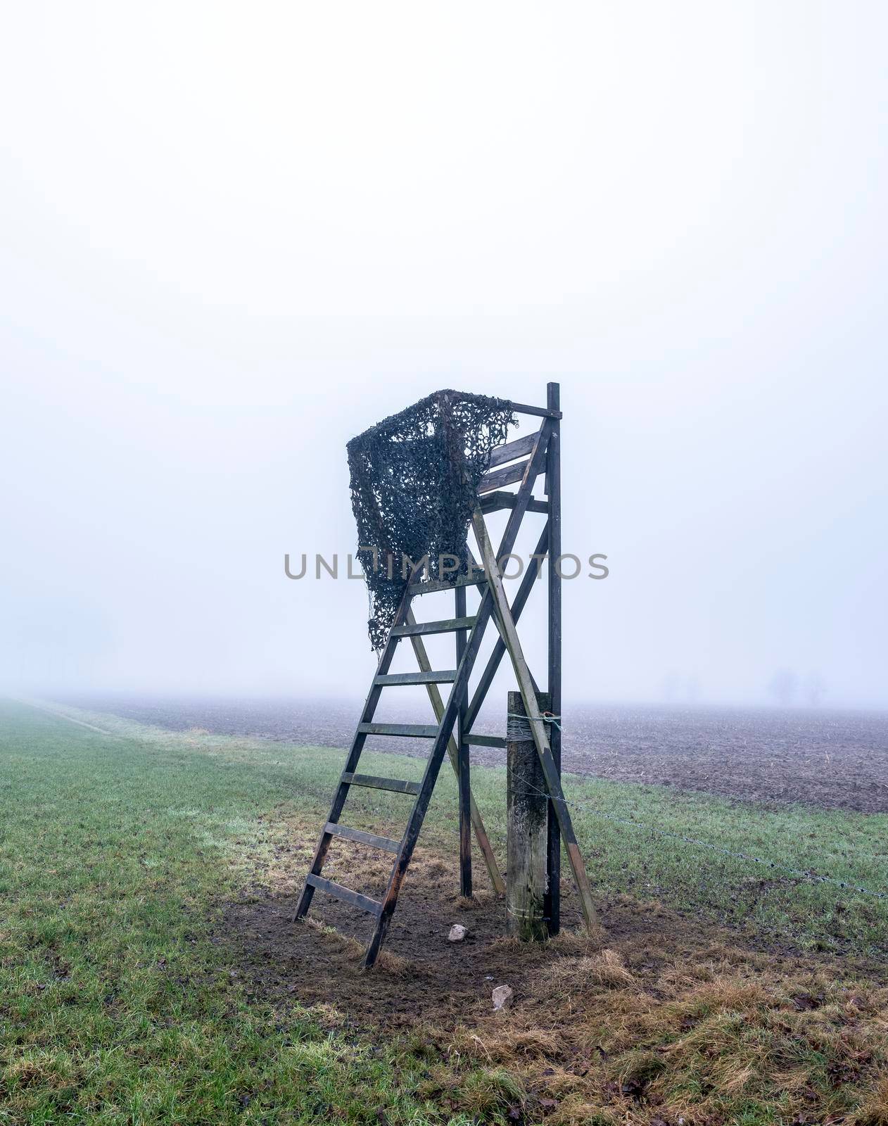high seat for hunting in green winter field near utrecht in the netherlands on misty winter day by ahavelaar