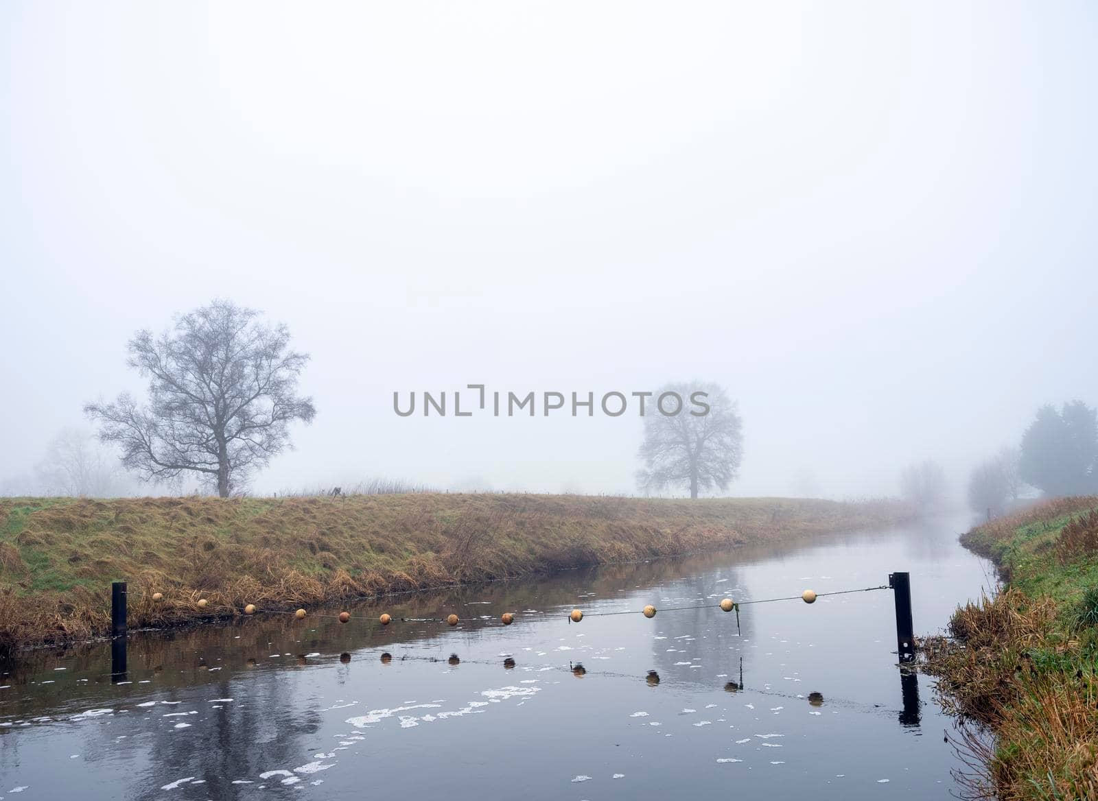 valleikanaal or valley canal near veenendaal in the netherlands on misty winter day by ahavelaar
