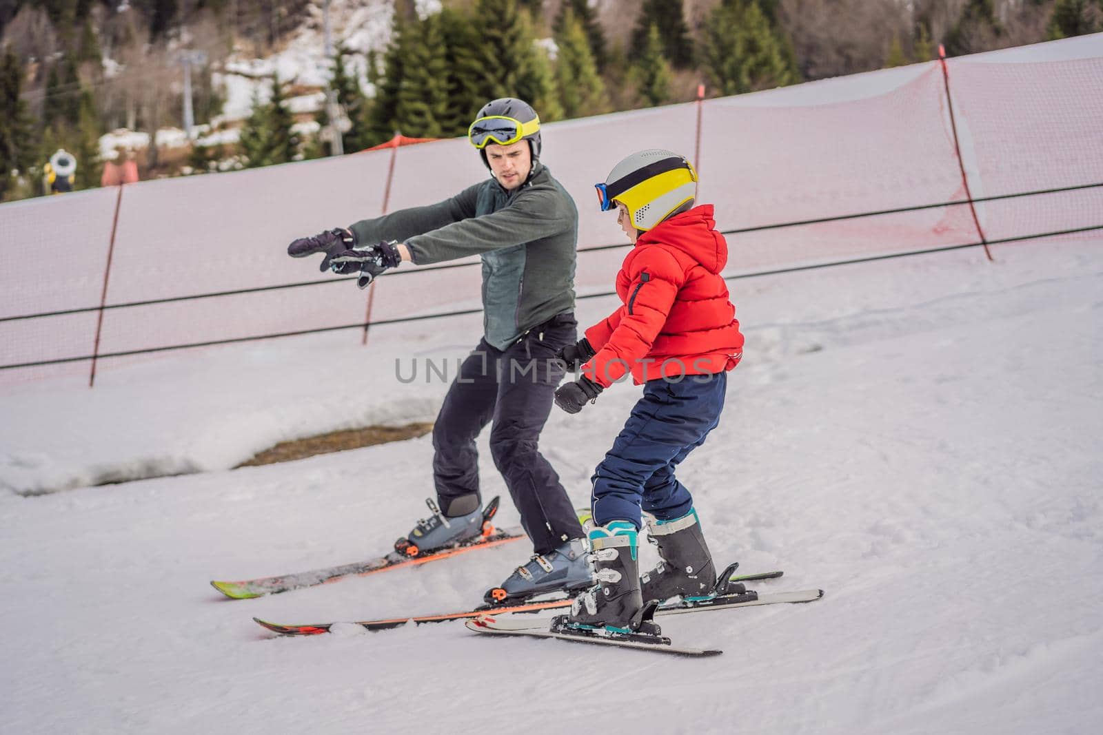 Boy learning to ski, training and listening to his ski instructor on the slope in winter by galitskaya