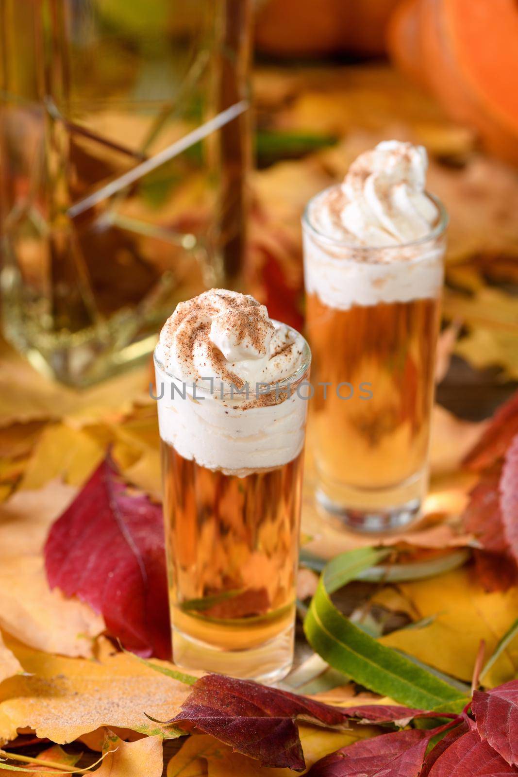 Two vodka with cream cinnamon pumpkin pie shooters in shot glasses. These drinks are easy to make and perfect for fall. Try these boozy drinks at your Halloween or Thanksgiving party