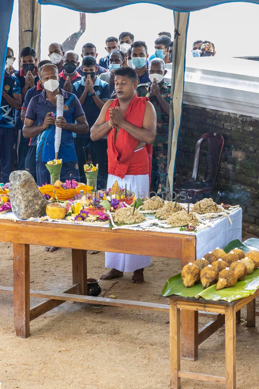 Anuradhapura Sri Lanka - december 6 2021: a sacred rite of prayer near a Buddhist temple. People are standing in front of a table with fruit and praying. A priest and musicians are present. High quality photo