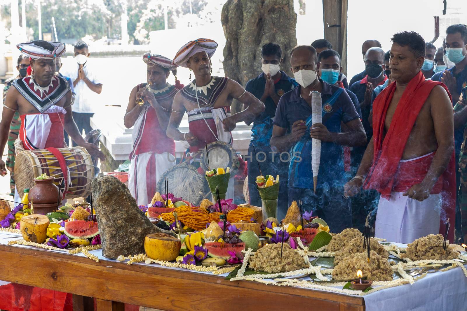 Anuradhapura Sri Lanka - december 6 2021: a sacred rite of prayer near a Buddhist temple. People are standing in front of a table with fruit and praying. A priest and musicians are present. High quality photo