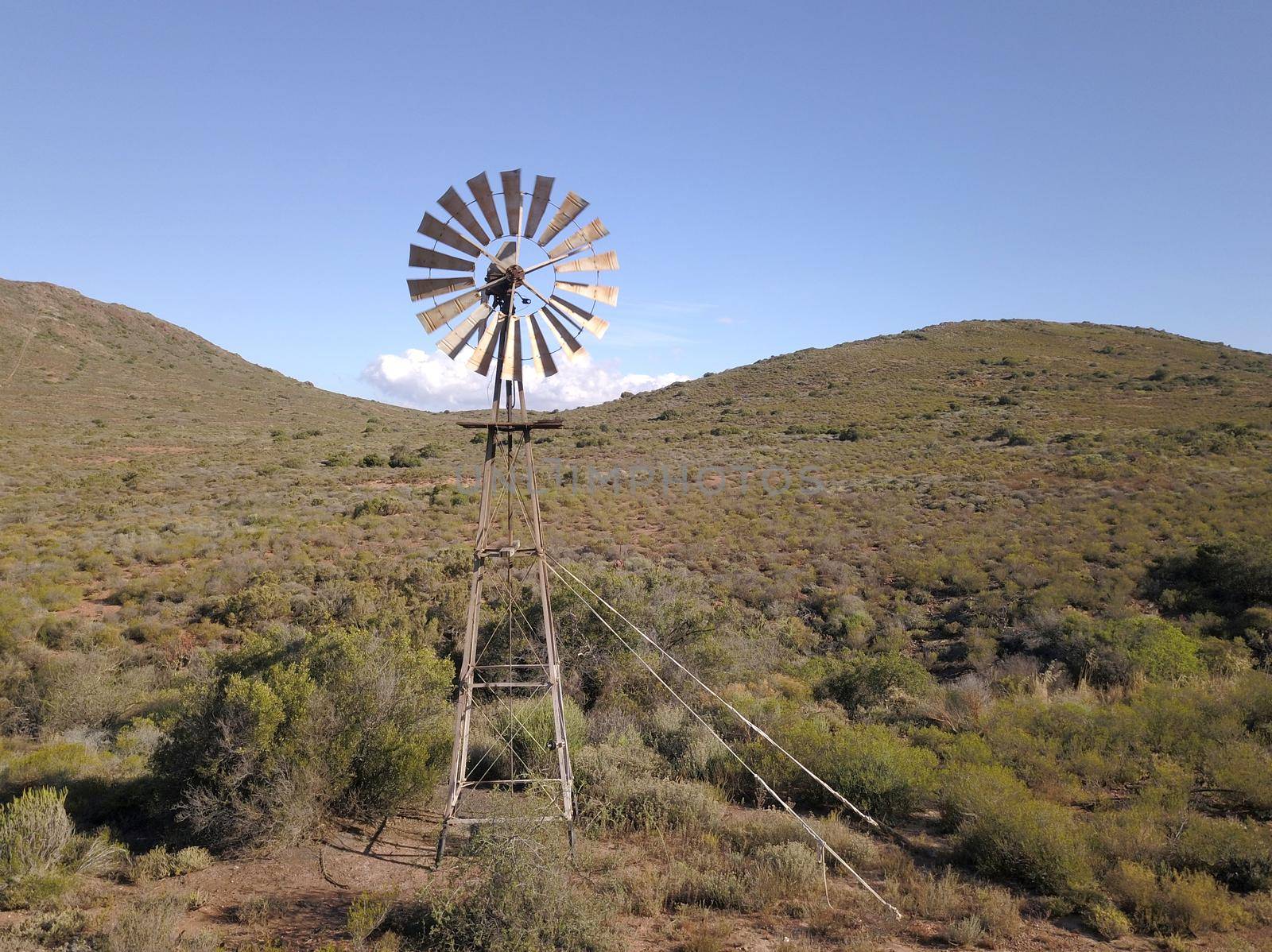 Windmill and water pump in dry landscape by fivepointsix