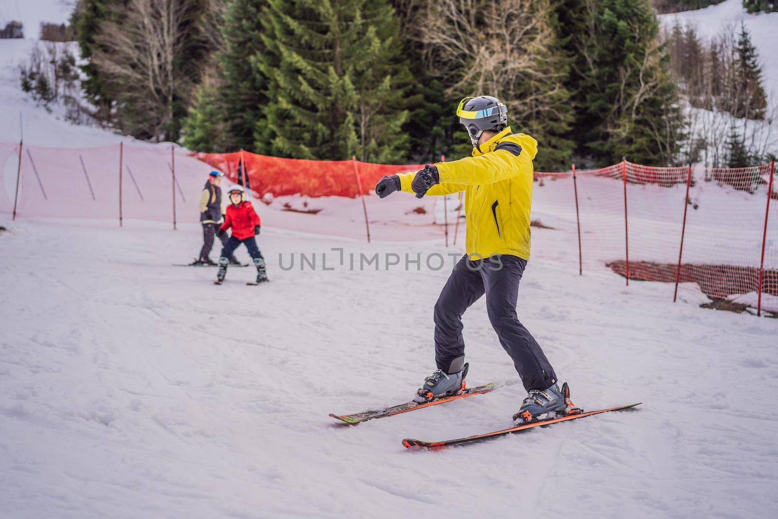 Mom and son are learning to ski with an instructor. Active toddler kid with safety helmet, goggles and poles. Ski race for young children. Winter sport for family. Kids ski lesson in alpine school. Little skier racing in snow by galitskaya