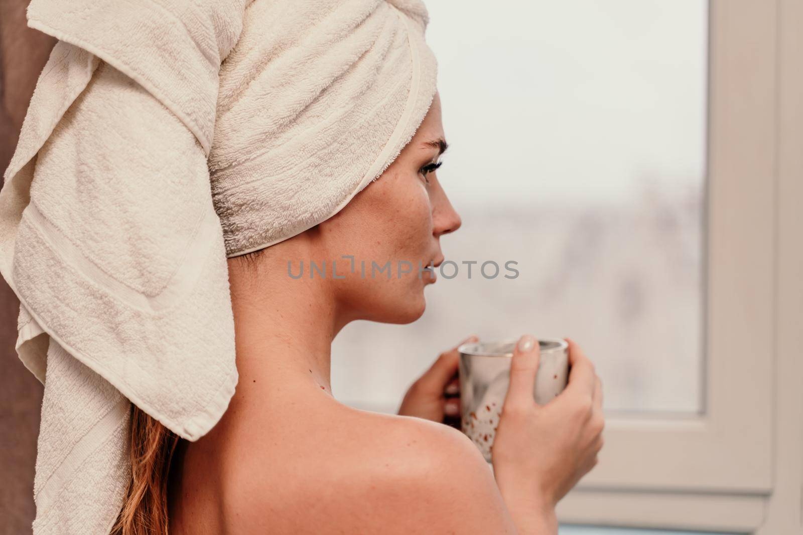 Young serene relaxed woman in spa bath towel drinking hot beverage tea coffee after taking shower bath at home. Beauty treatment, hydration concept. by Matiunina