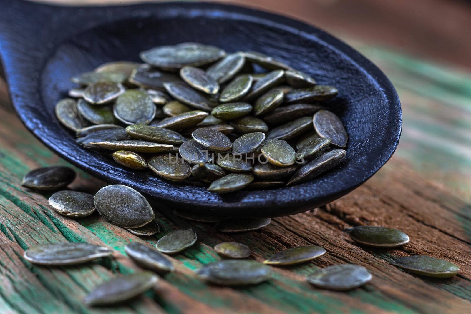 spoon of squash seeds on old wooden table background