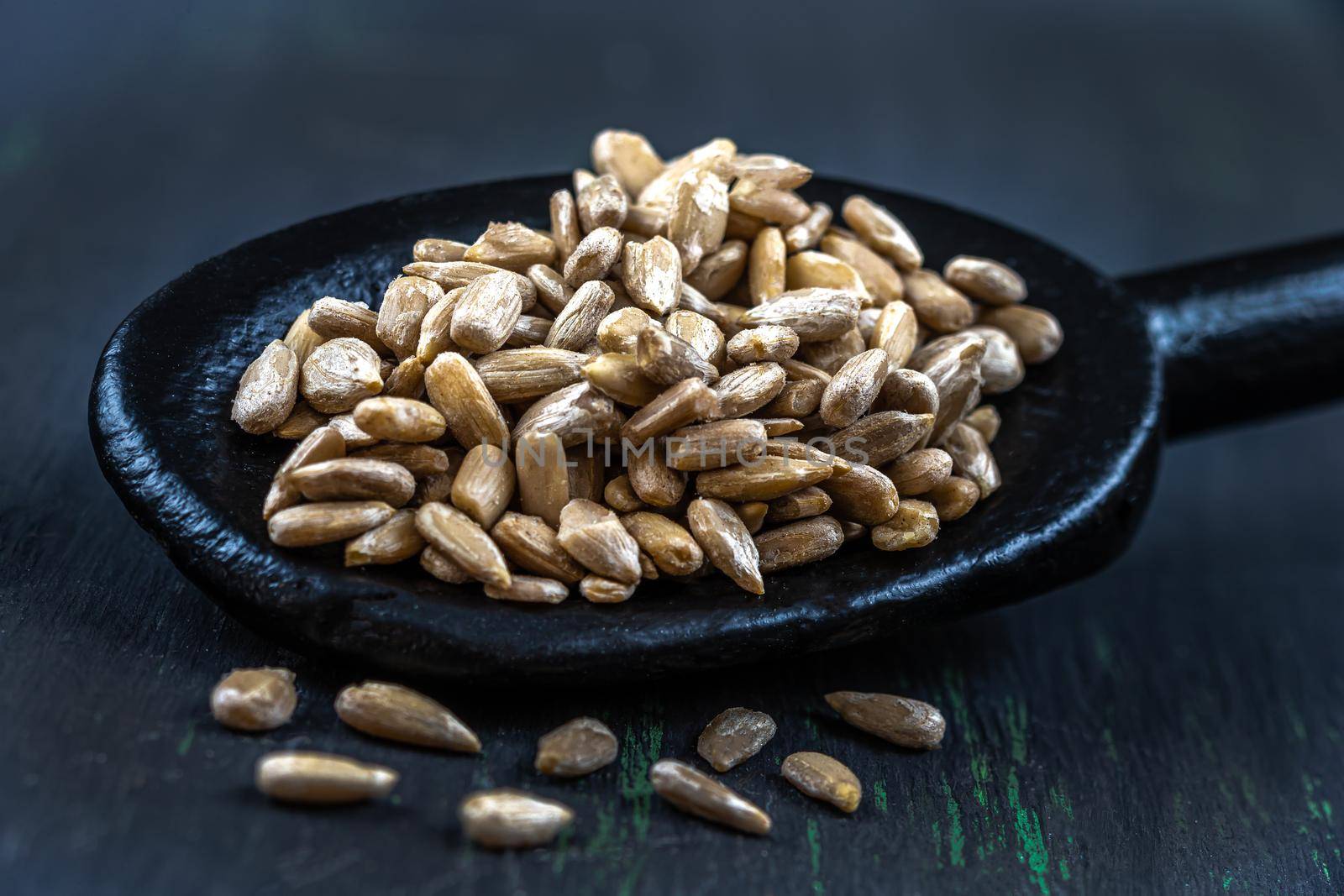 Sunflower seeds in macro in a black wooden spoon