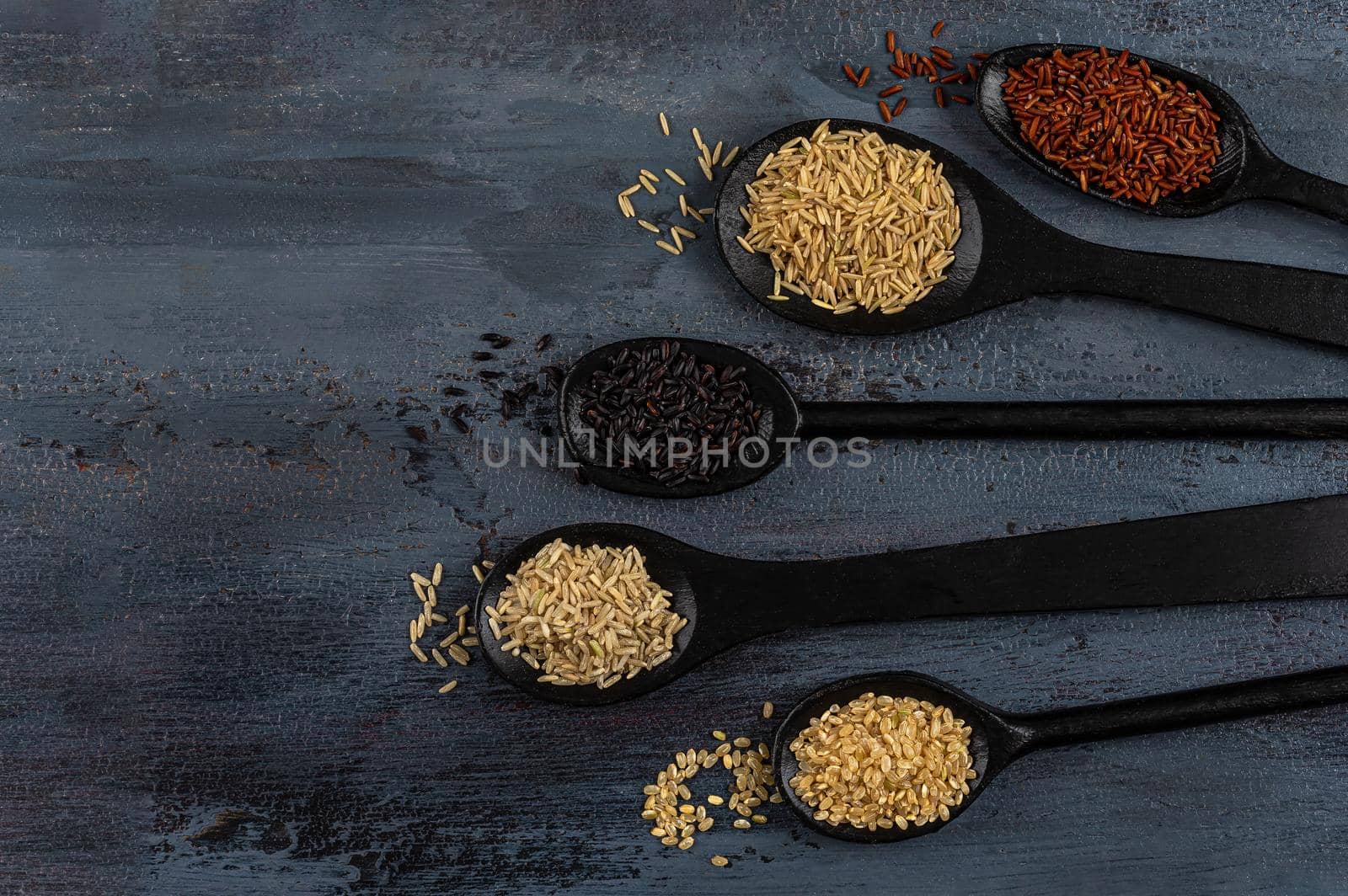 Basmati rice, long rice, black rice, round rice in wooden spoons-view from above