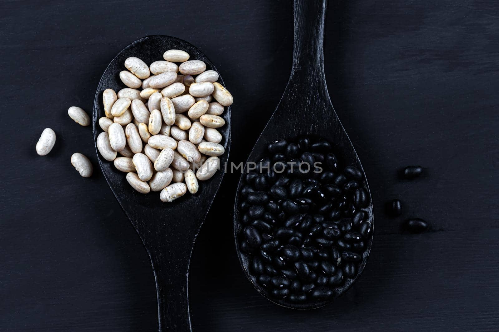 Contrast of beans in spoons seen from above on a black background