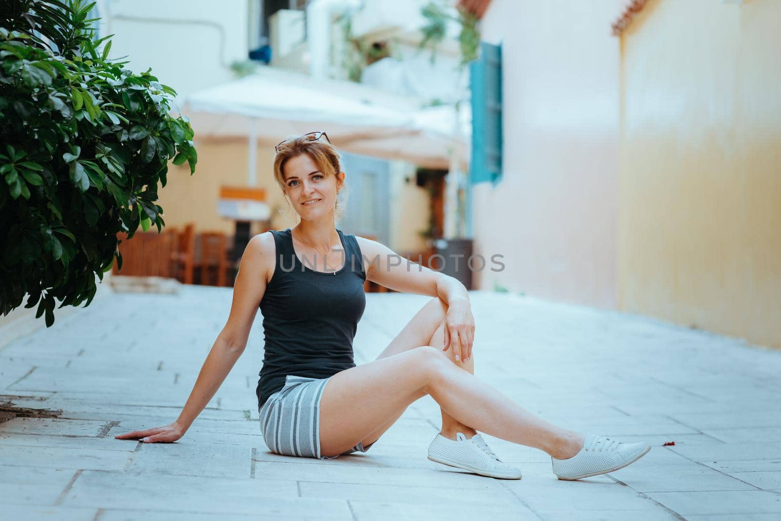 Beautiful girl walking along the street of an old European town with a film camera in her hand. Portrait of a tourist girl walking on the street background. by Andrii_Ko