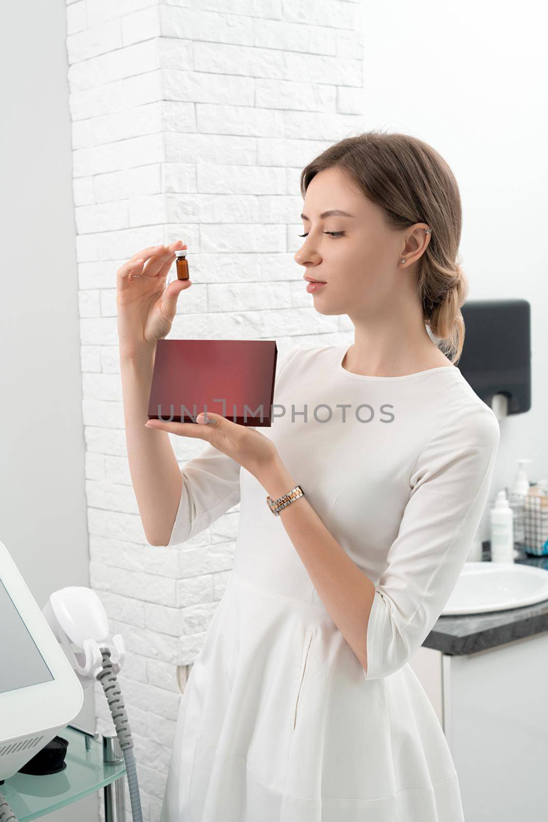 Cosmetologist dermatologist holds a package with drugs for facial rejuvenation. A female doctor in office shows treatment options. Mockup with copy space by Mariakray