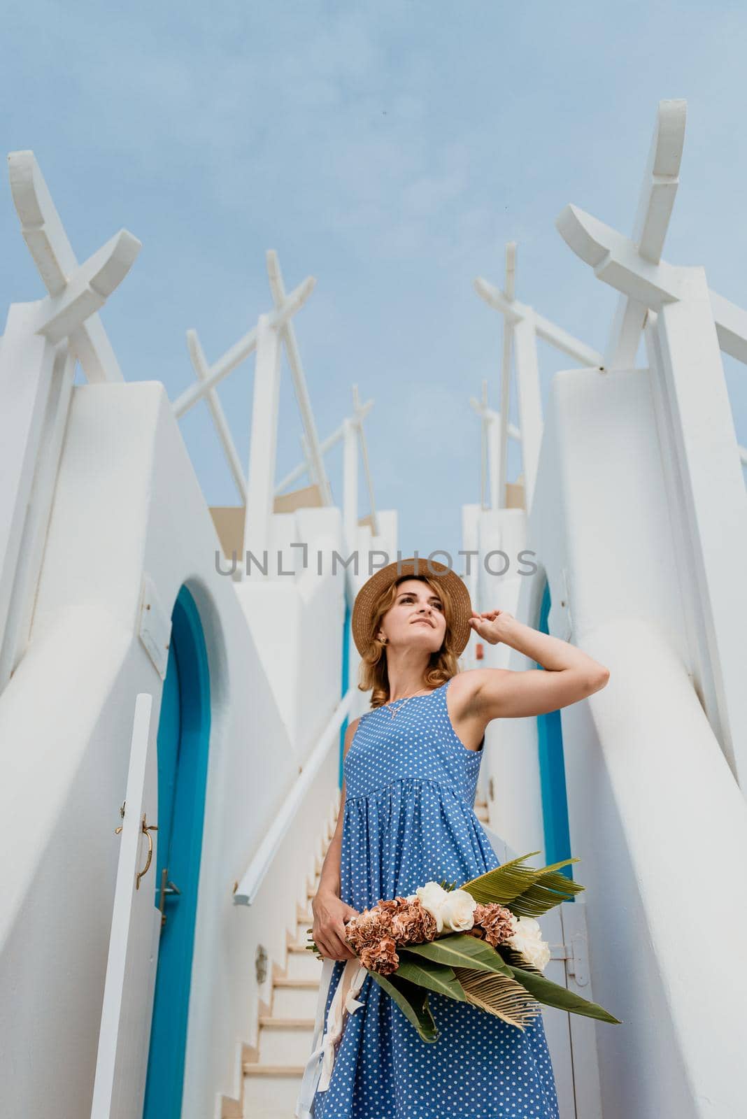 Beautiful girl walking along the street of Santorini island, an old European town, Greece. Portrait of a tourist girl walking on the street background