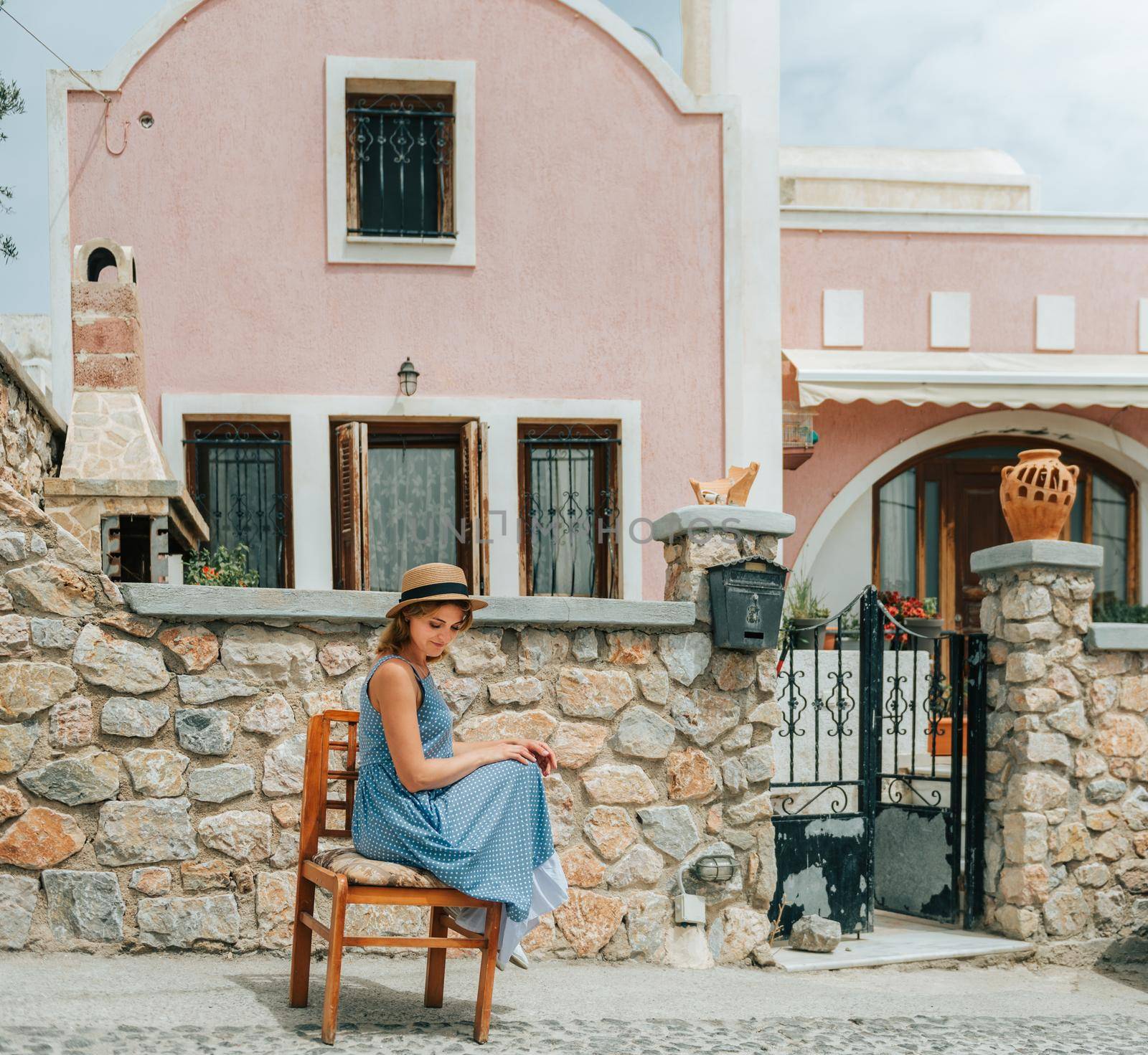 Travel Europe for summer holiday. Portrait of beautiful woman visitting old villages in Greecem with sun hat and summer dress.