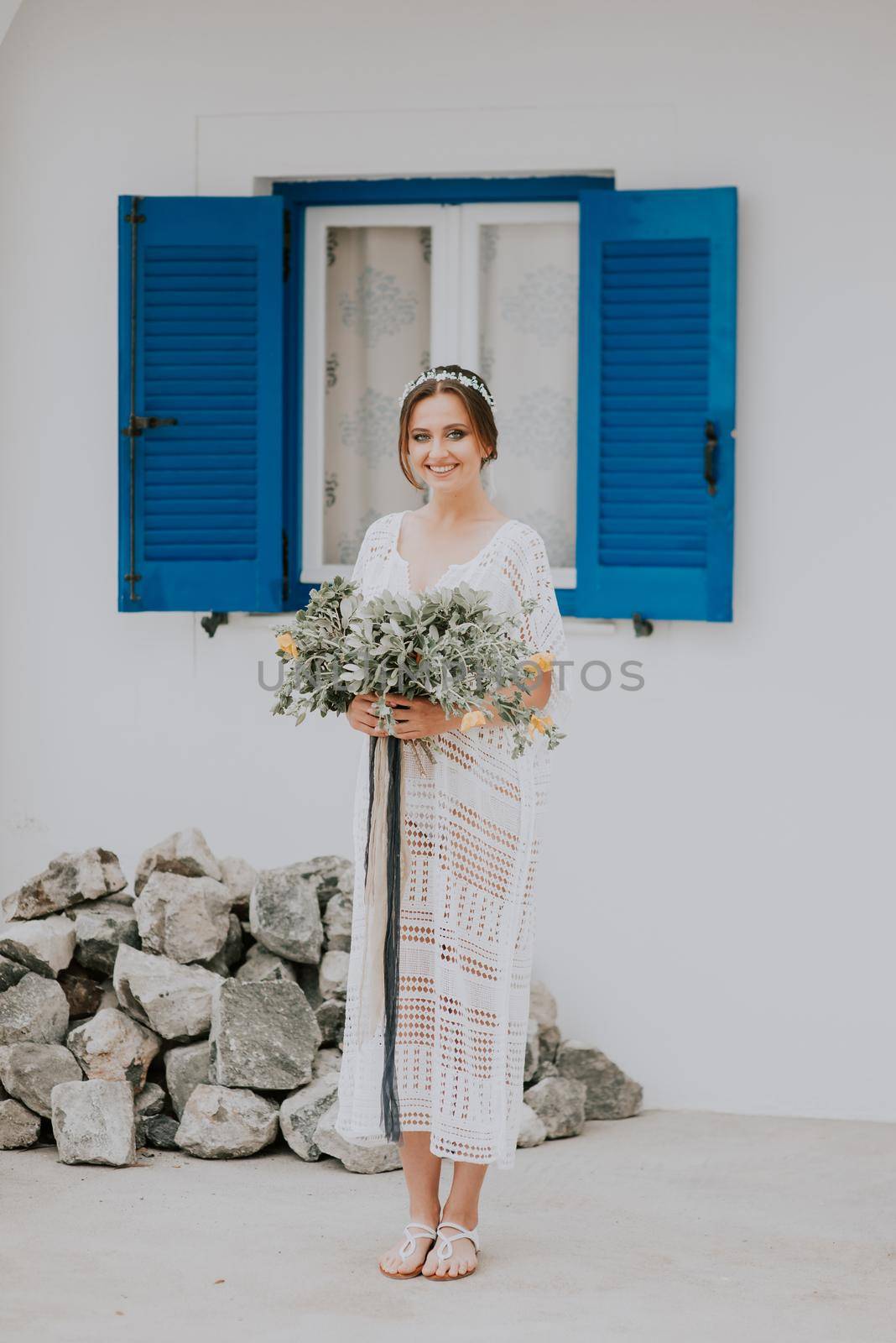 Beautiful bride on a background of white architecture with blue window on Santorini island, Greece,a popular wedding destination by Andrii_Ko