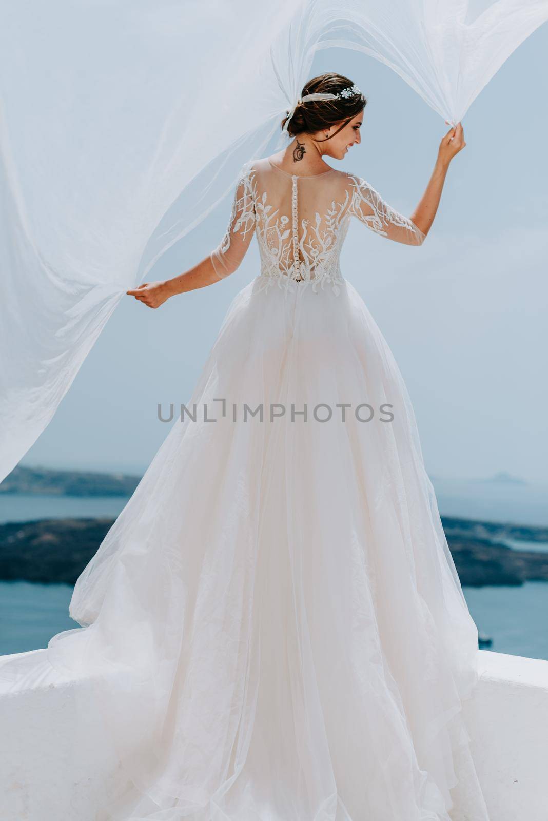 Romantic beautiful bride in white dress posing on terrace with sea and mountains in background by Andrii_Ko