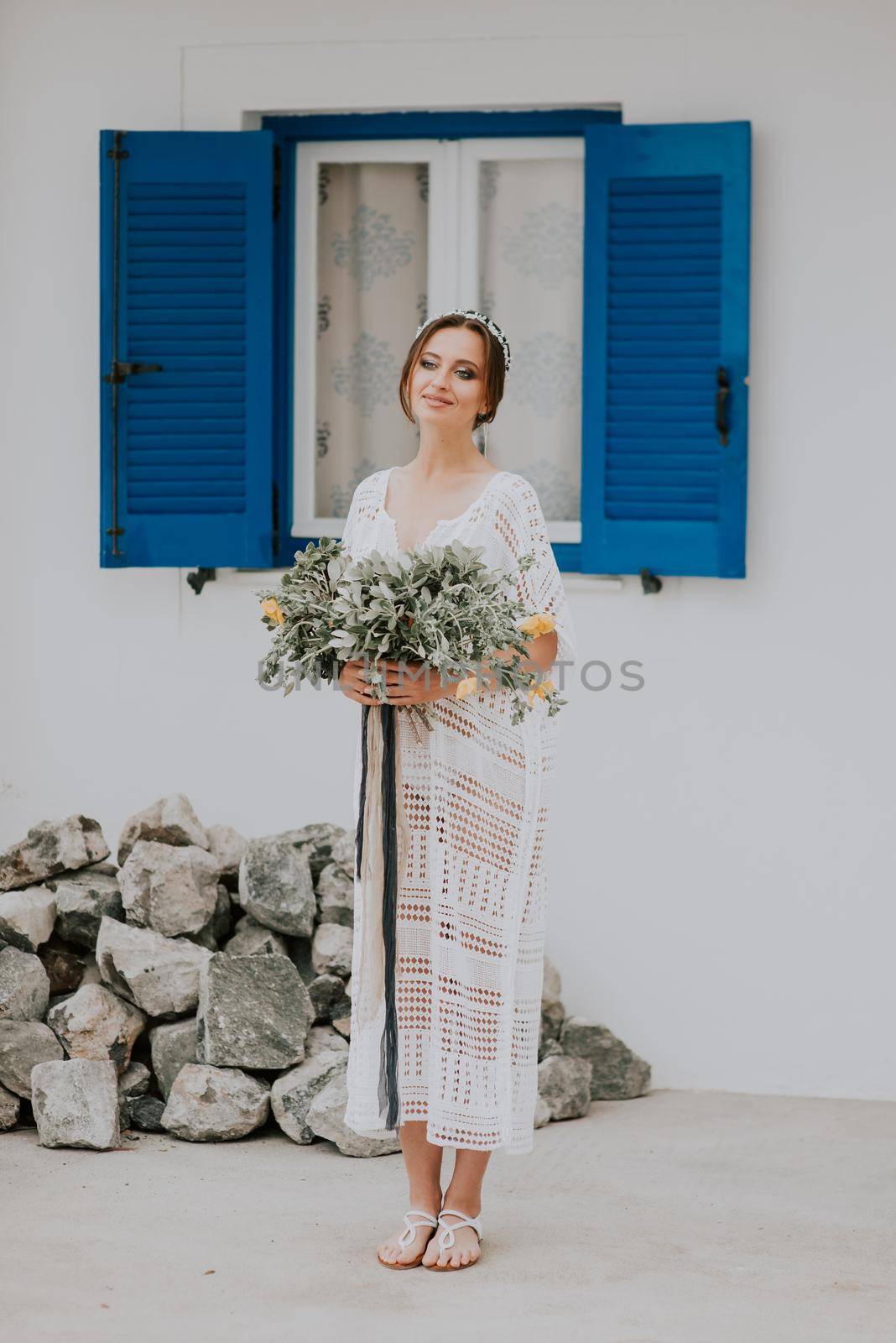 Beautiful bride on a background of white architecture with blue window on Santorini island, Greece,a popular wedding destination by Andrii_Ko