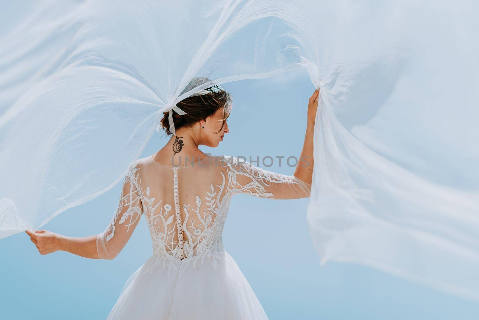 Romantic beautiful bride in white dress posing on terrace with sea and mountains in background by Andrii_Ko