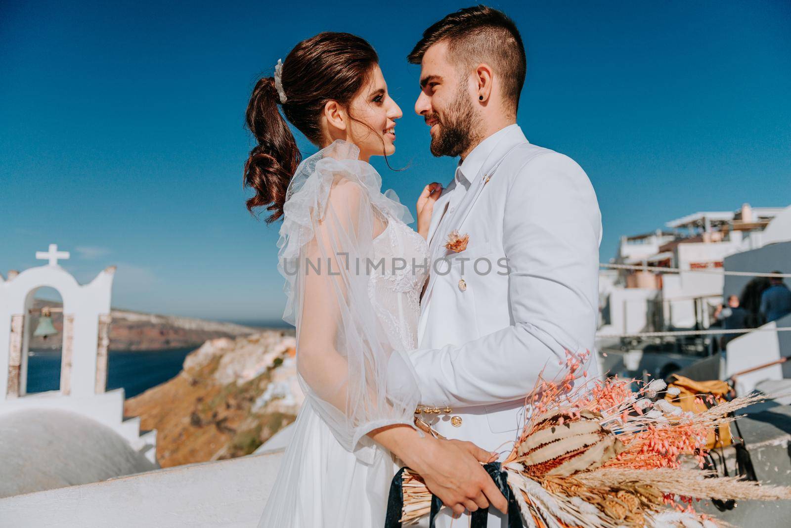 beautiful bride and groom in their summer wedding day on greek island Santorini by Andrii_Ko