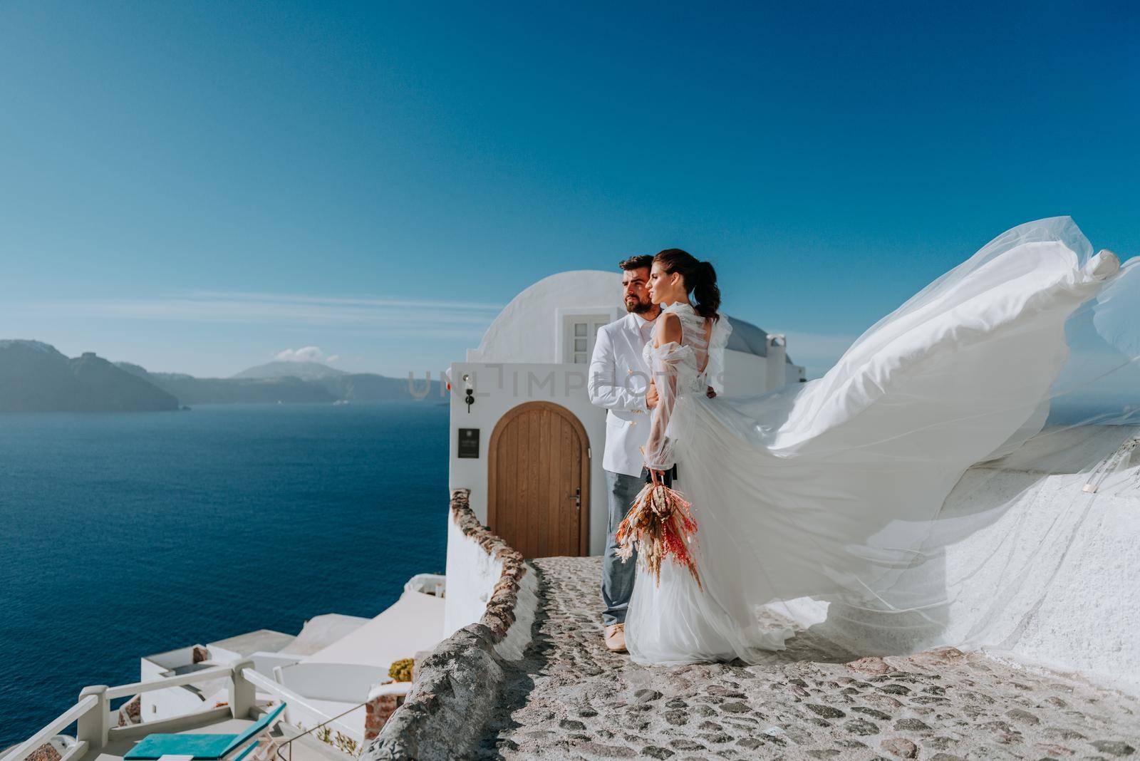 beautiful bride and groom in their summer wedding day on greek island Santorini by Andrii_Ko