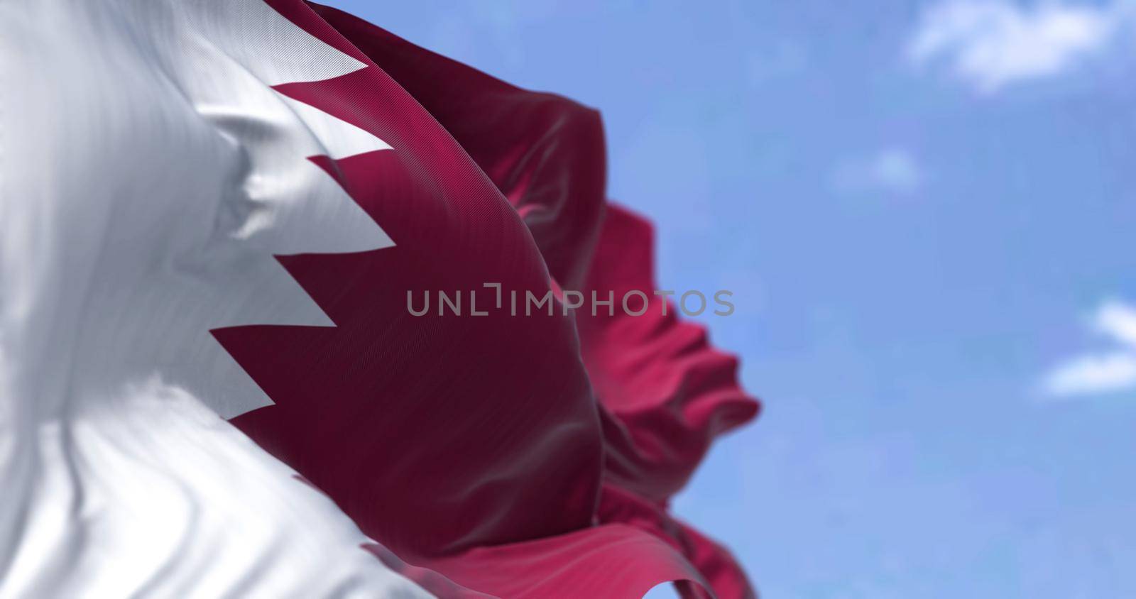 Detail of the national flag of Qatar waving in the wind on a clear day. Western asia country. Patriotism. Selective focus.