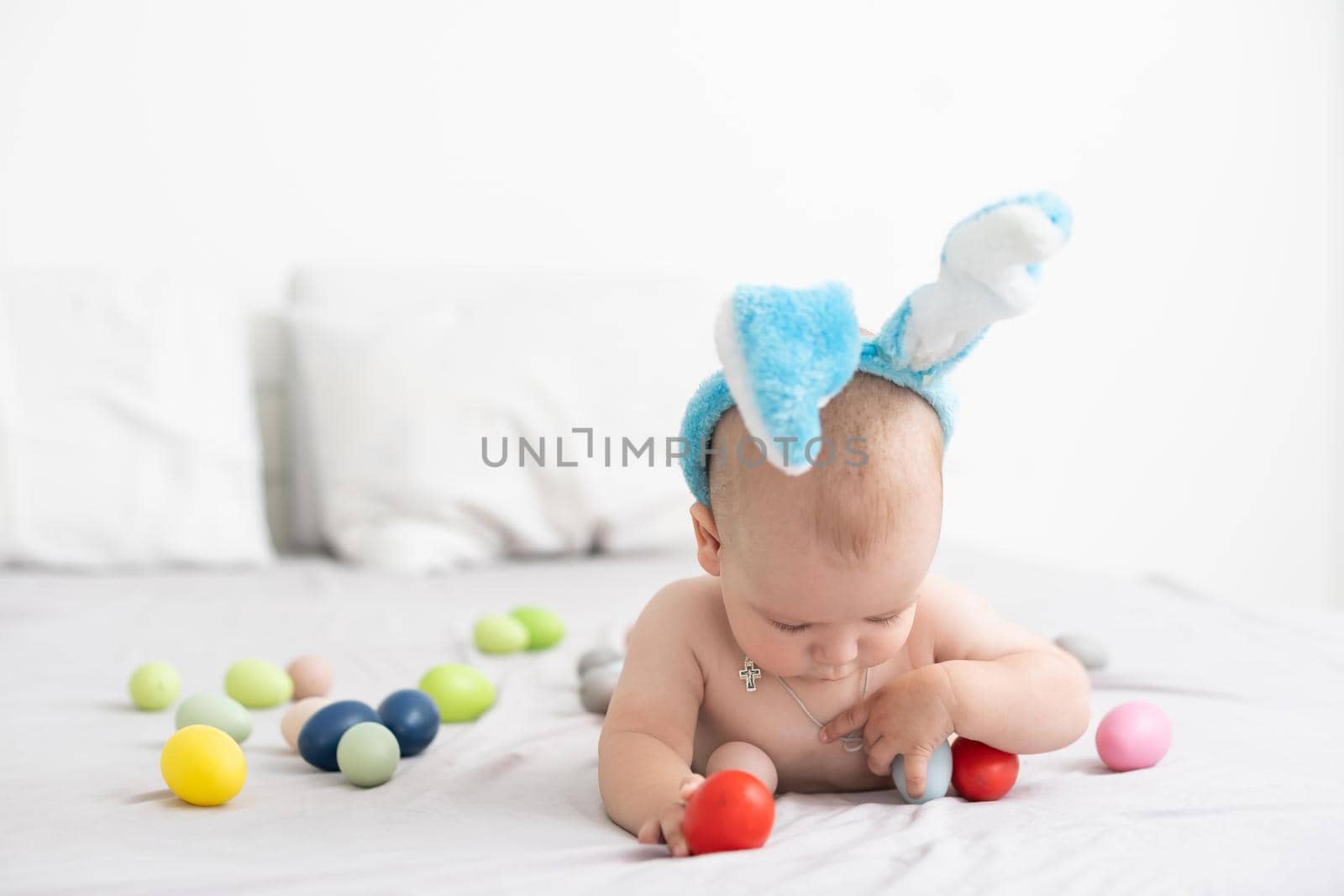 Portrait of a cute baby dressed in Easter bunny ears with a basket full of eggs by Andelov13