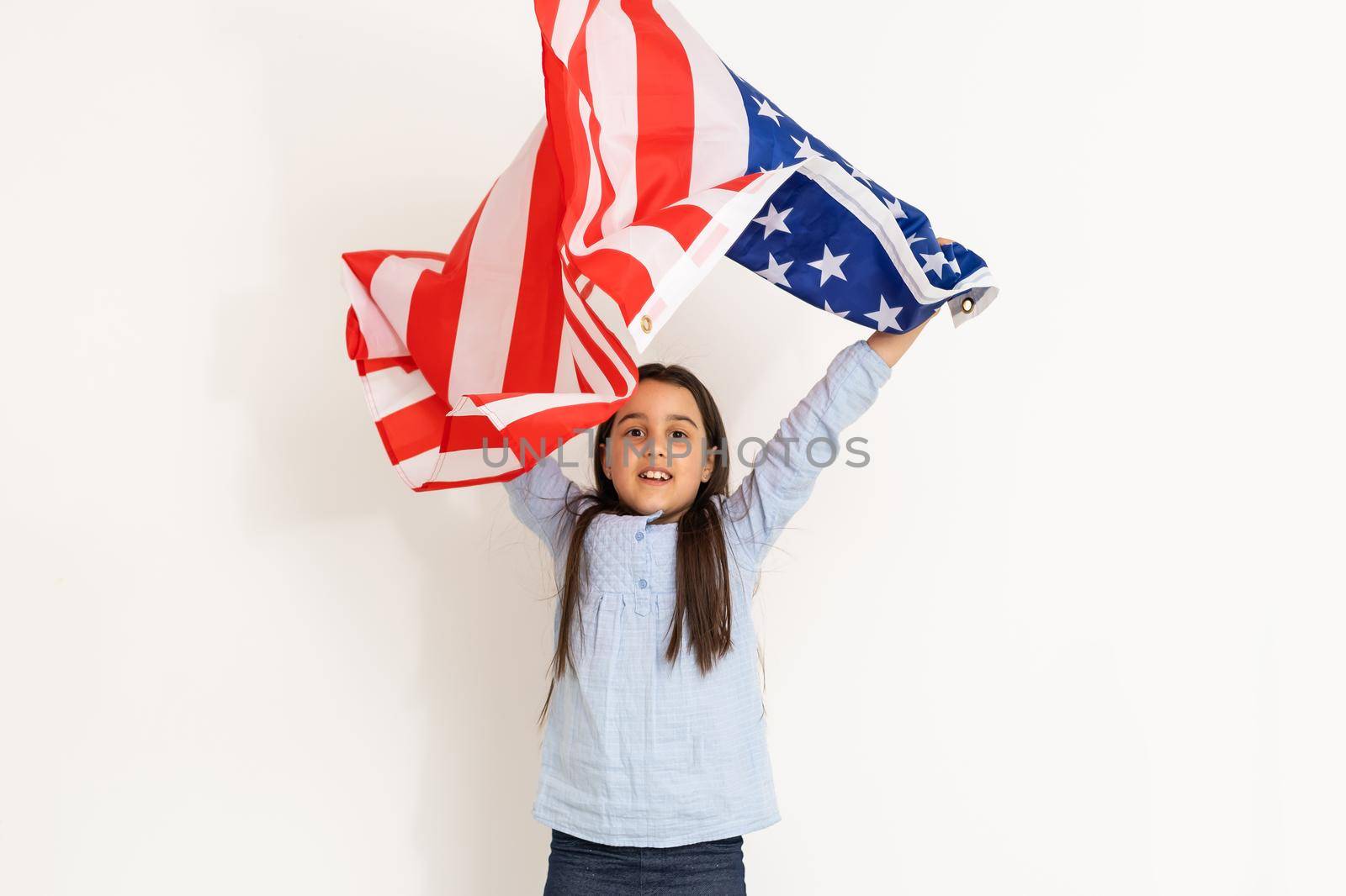 Patriotic holiday. Happy kid, cute little child girl with American flag. USA celebrate 4th of July