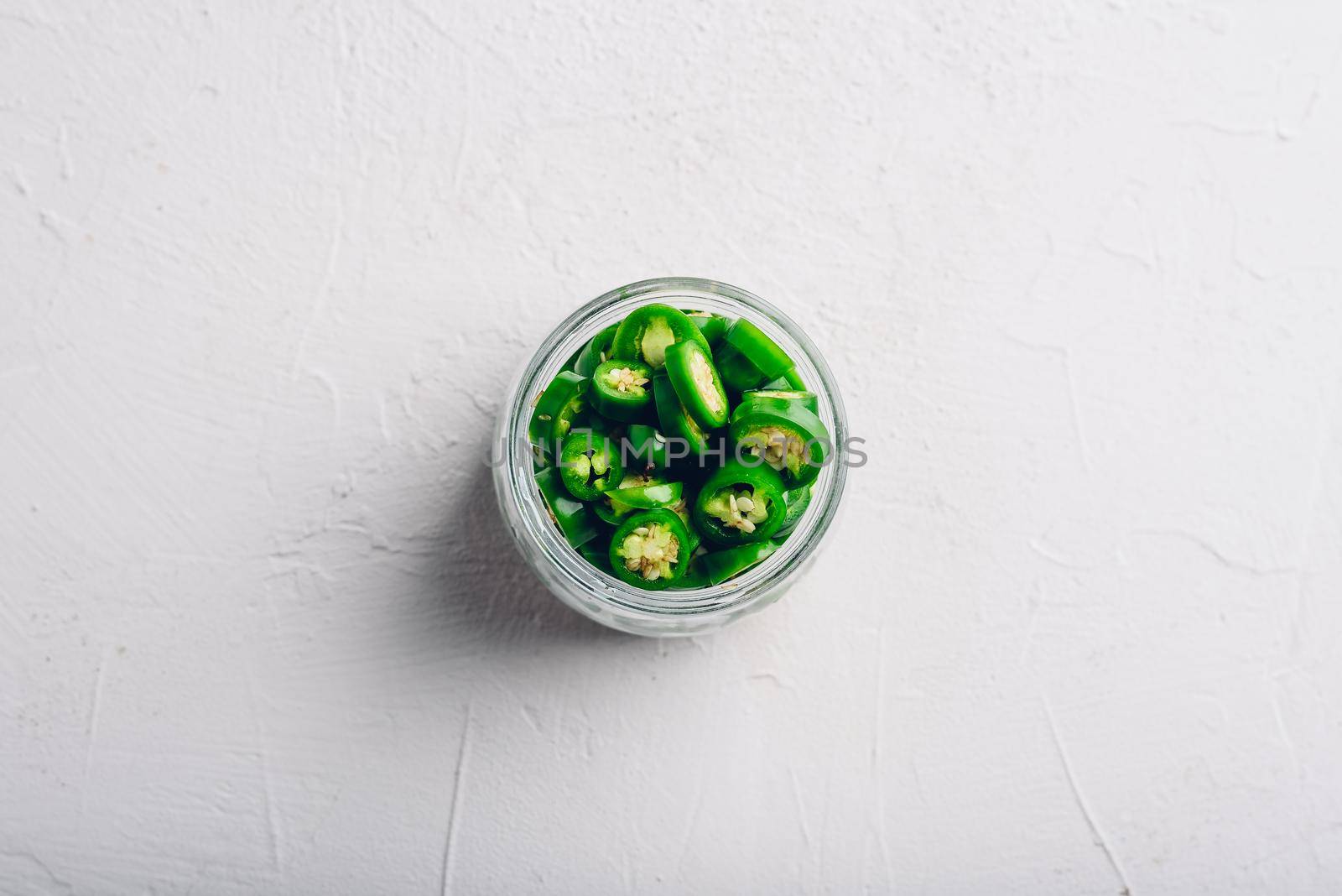 Sliced Jalapeno Peppers in Glass Jars for Canning on Light Concrete Background. View from Above