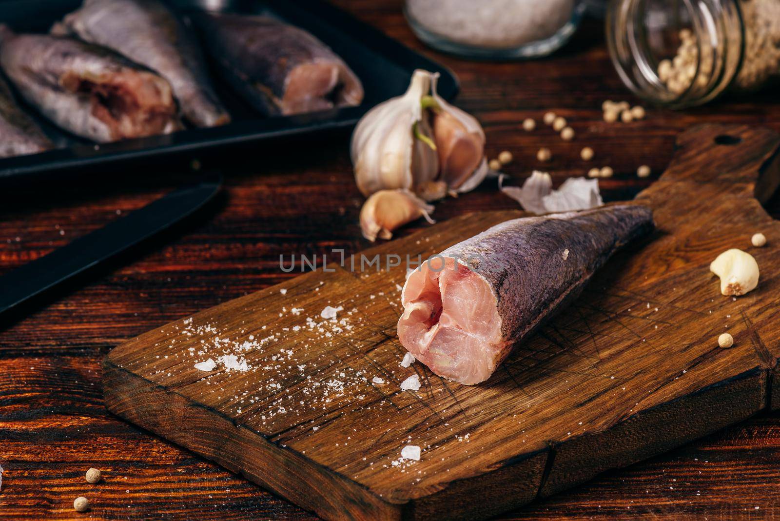 Hake carcasses on cutting board with spices and vegetables