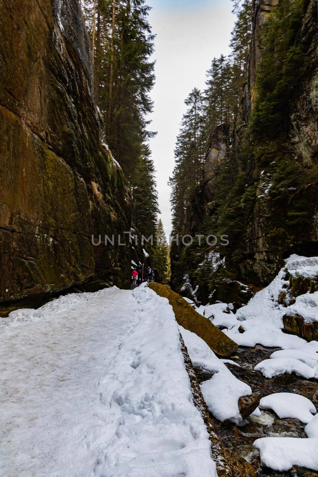 Small footbridge over mountain river between high rocks as path to waterfall