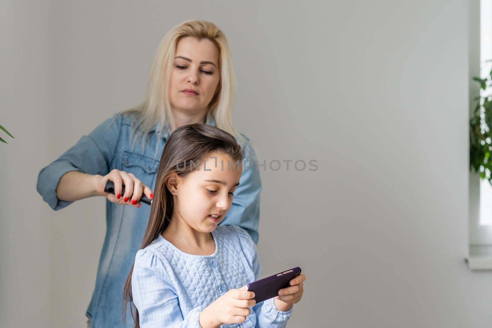 Mom combing hair of his daughter.