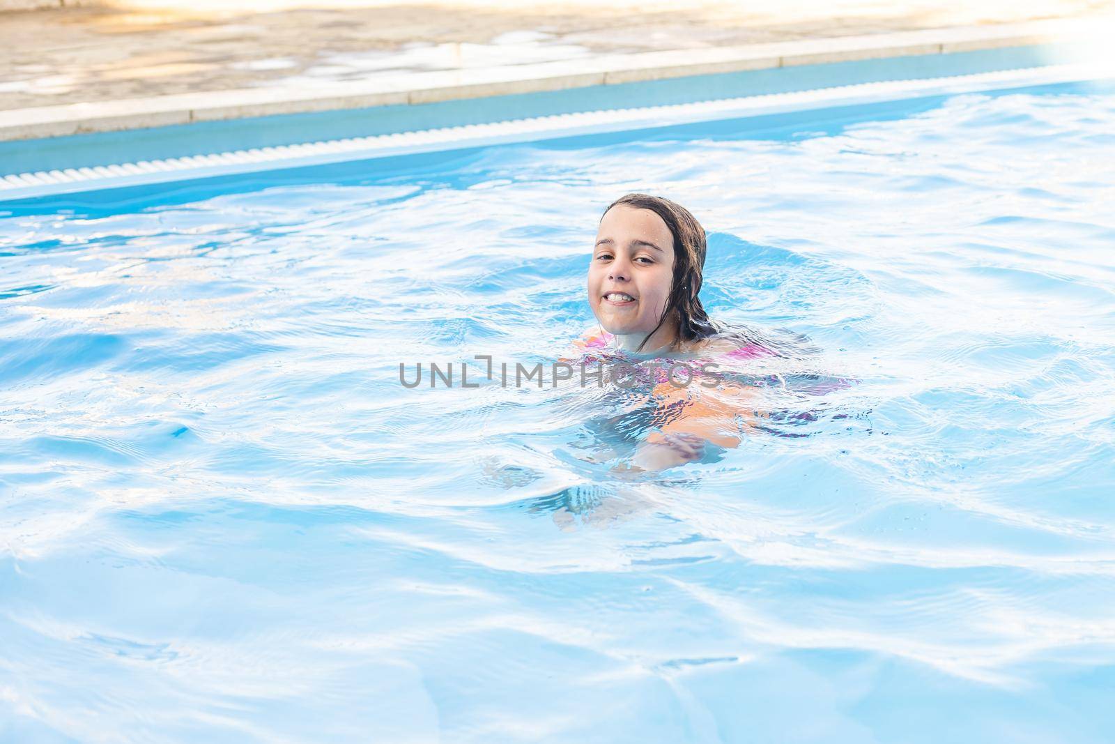 happy little girl having fun in the pool in swimming suit