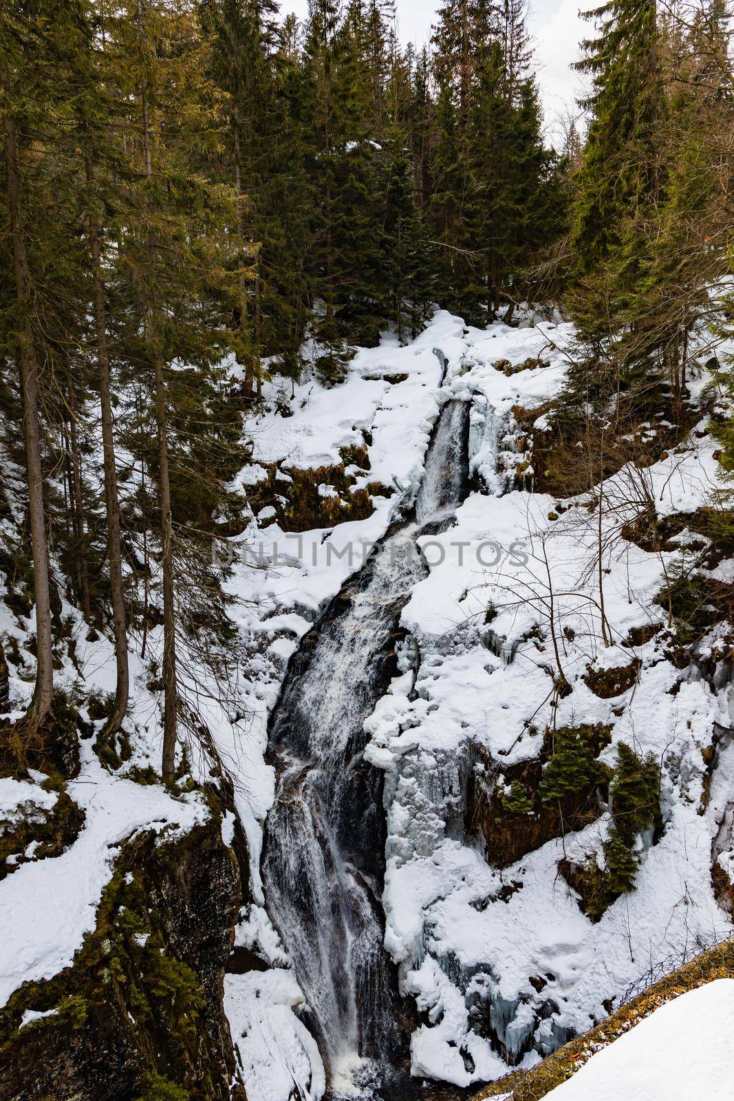 Long high waterfall in mountains full of snow and ice around by Wierzchu