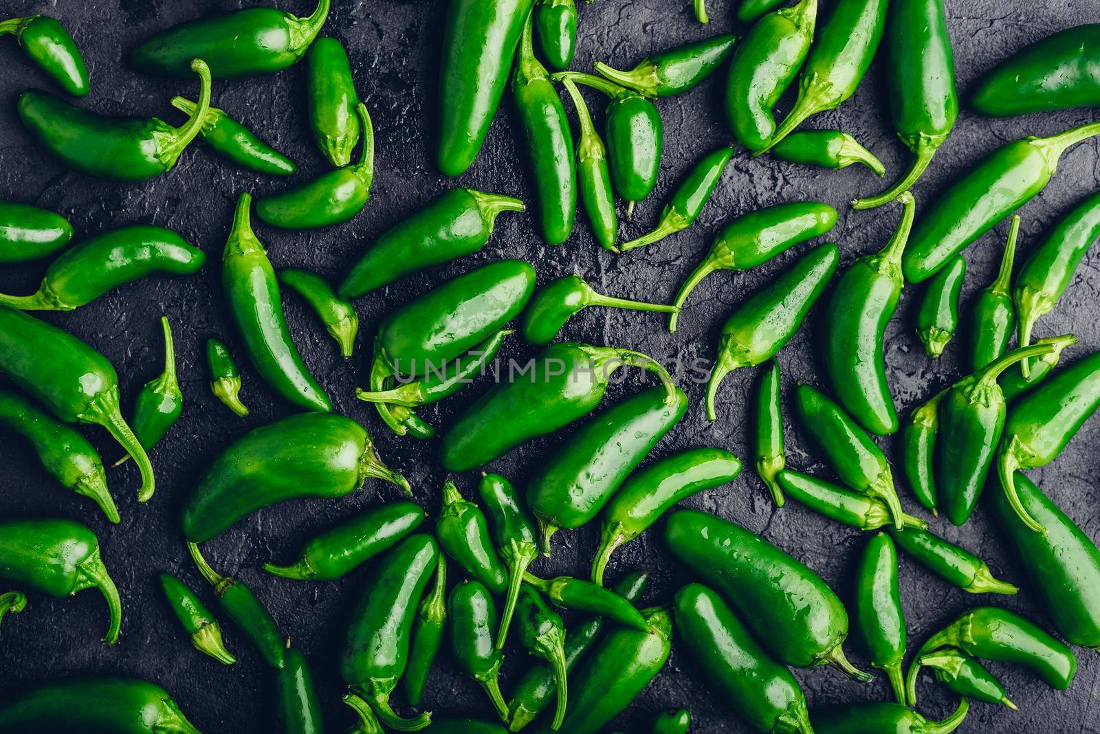 Top View of Arranged Green Jalapeno Peppers on Dark Concrete Background