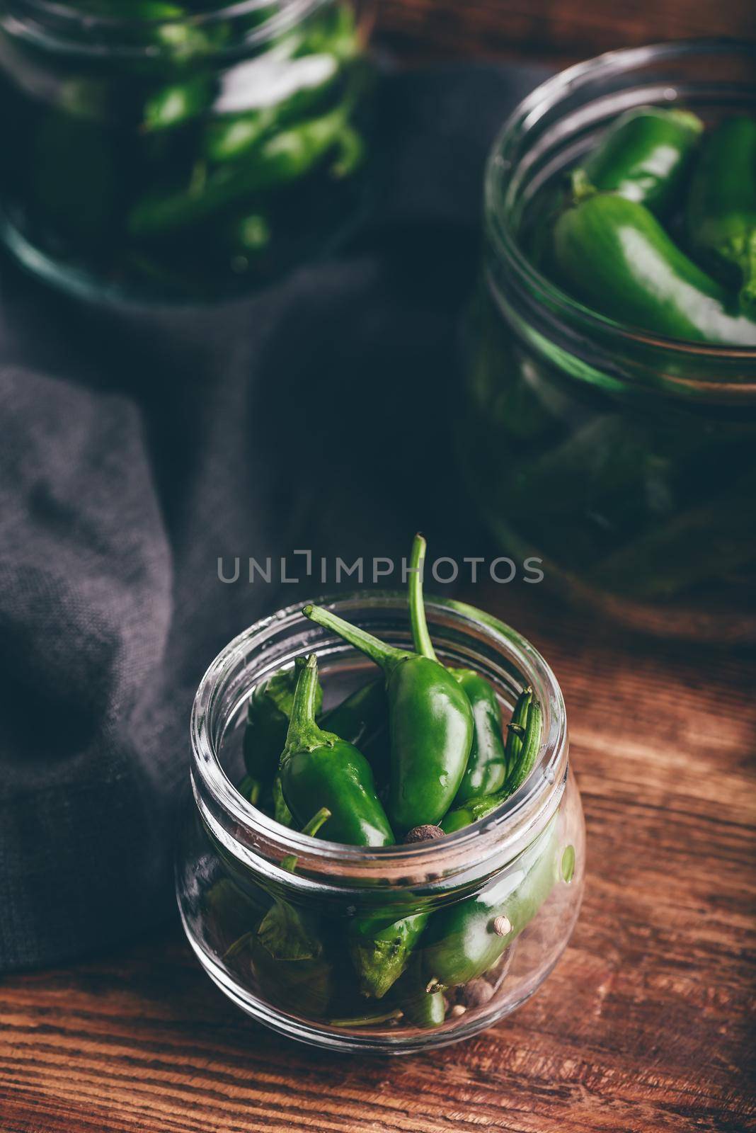 Jalapeno Peppers in Glass Jars for Canning with Dill and Garlic on Wooden Table