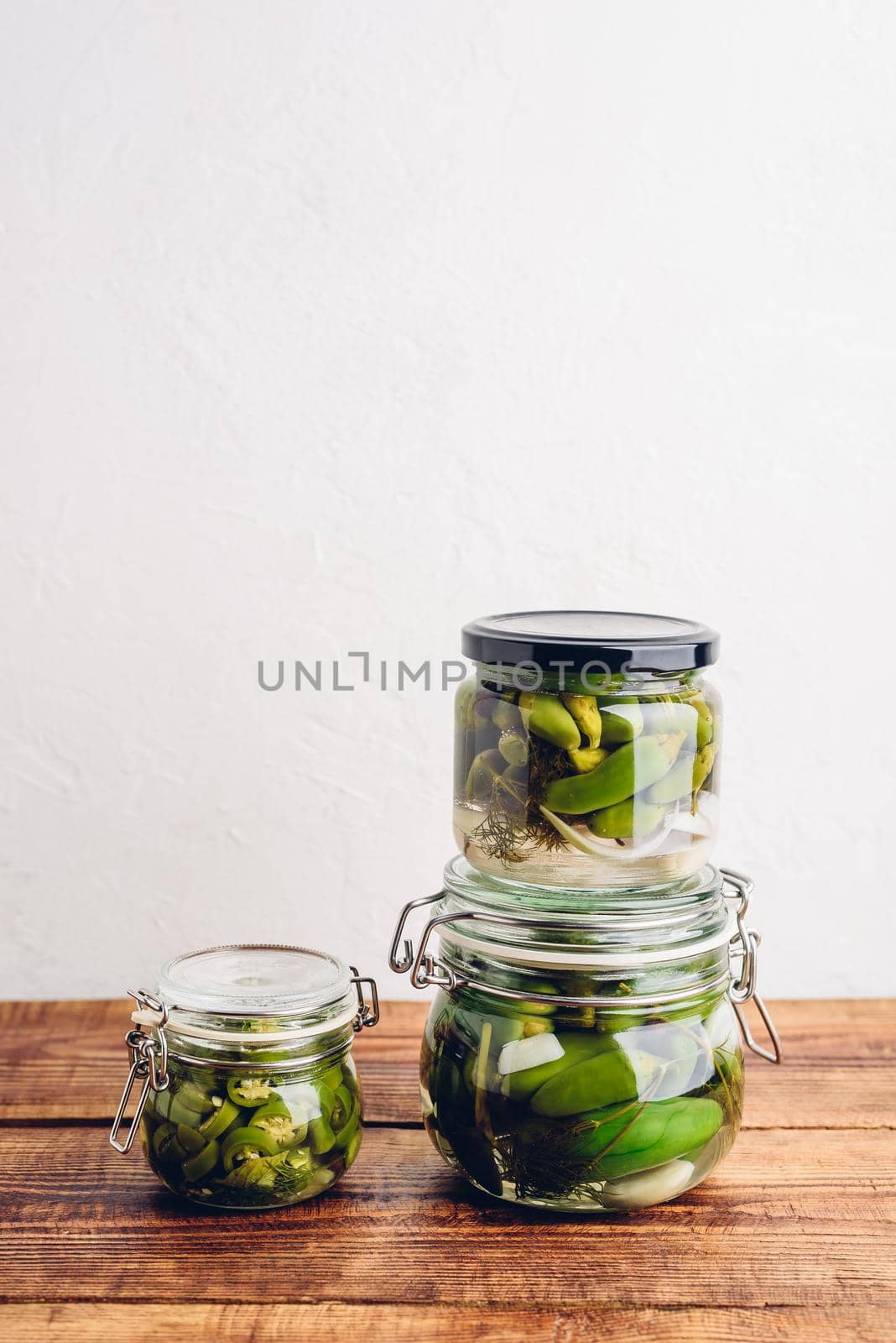 Three Jars of Freshly Pickled Jalapeno Peppers on Wooden Table. Copy Space