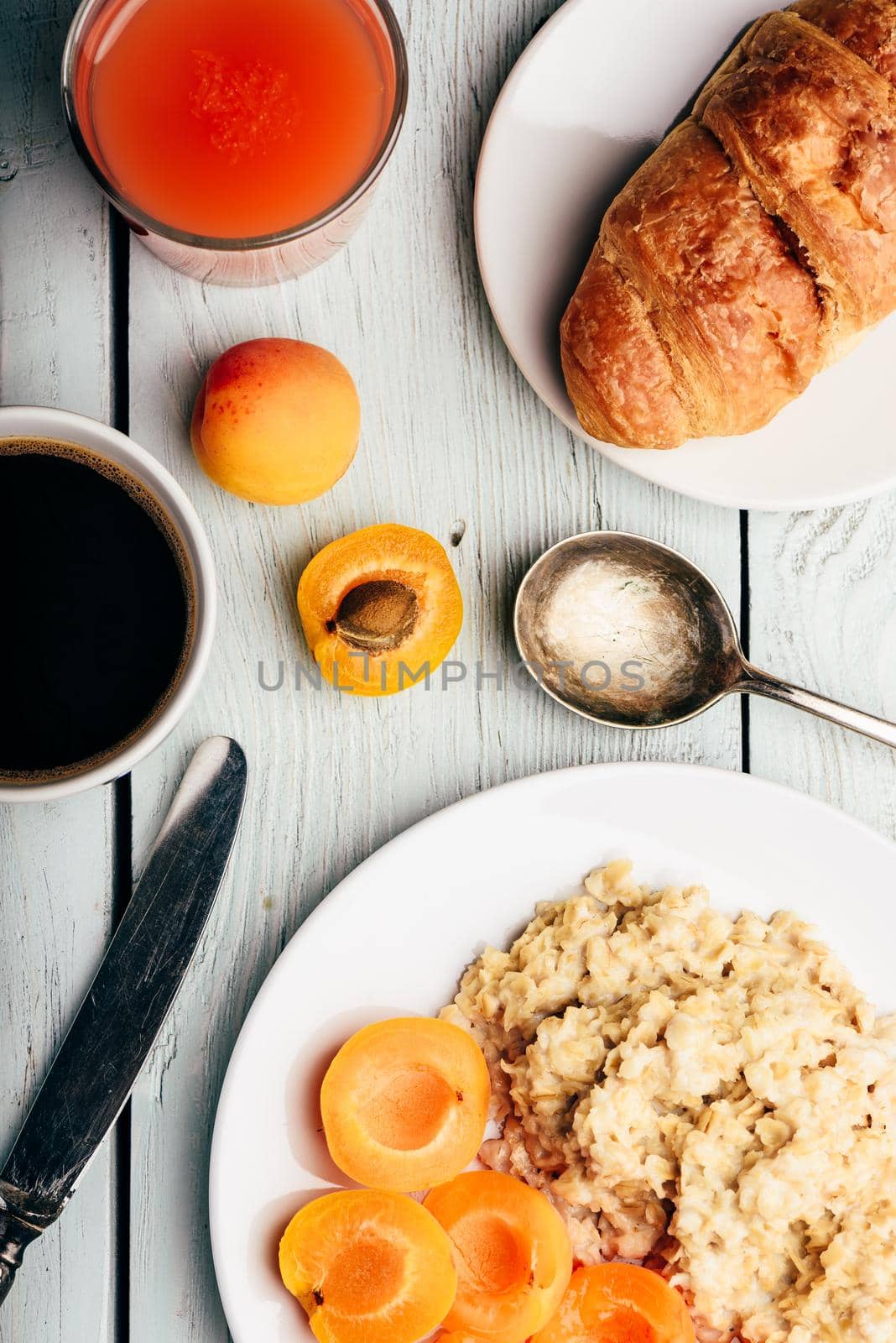 Porridge with apricot, coffee, glass of juice and croissant by Seva_blsv