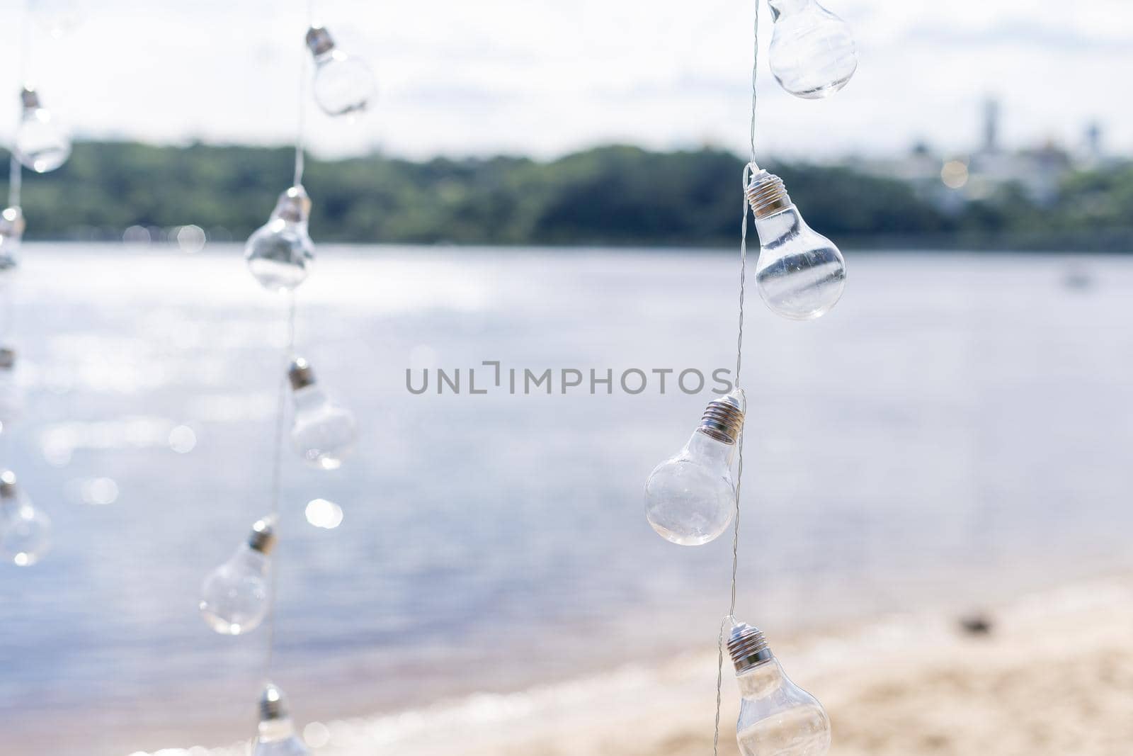 Hanging light bulbs on a background of water by Andelov13