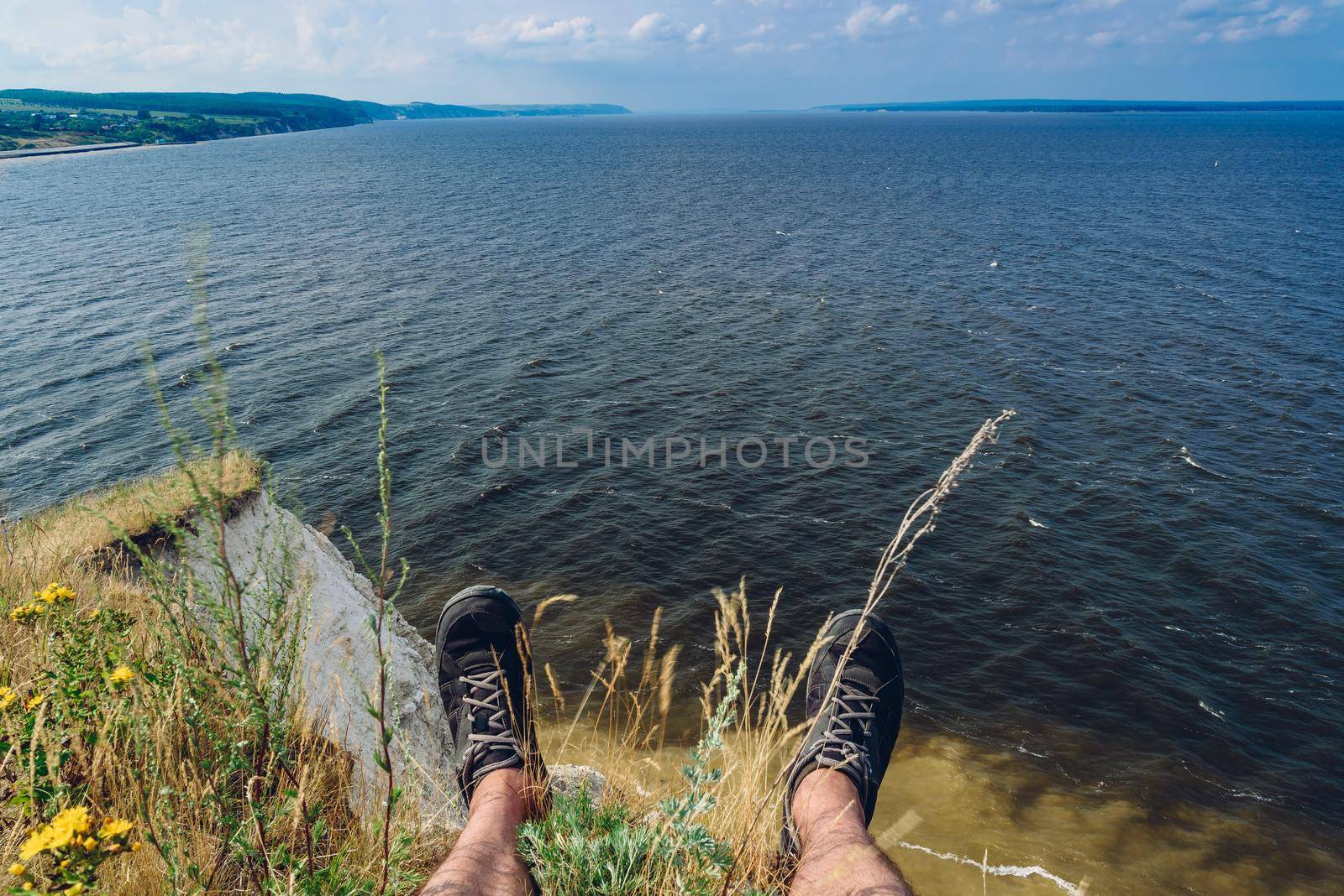 POV point of view of man sitting on the edge of cliff looking down at the river