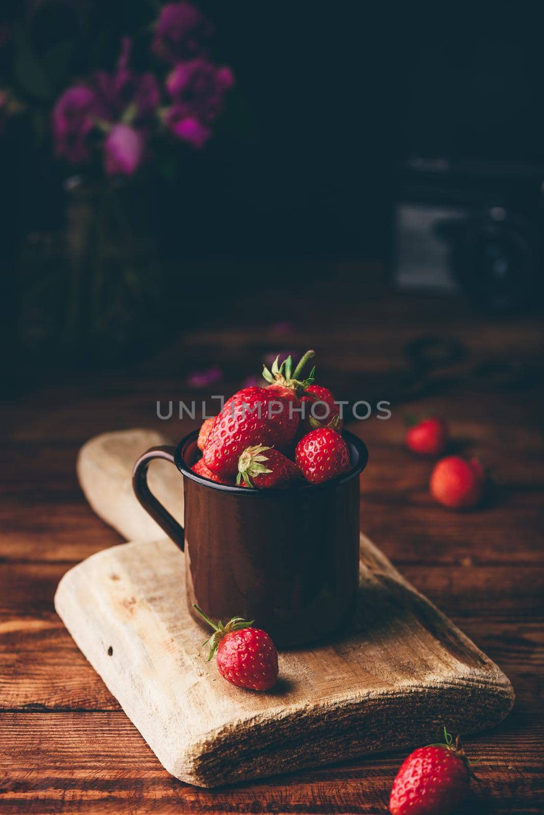 Fresh red strawberries in metal mug on table.