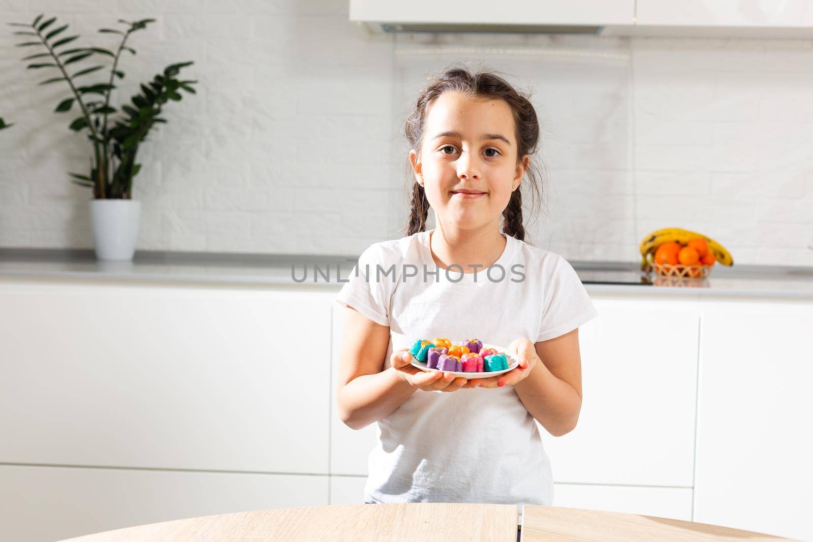 Small girl celebrating Holi Festival of Colors holding tray in hand.