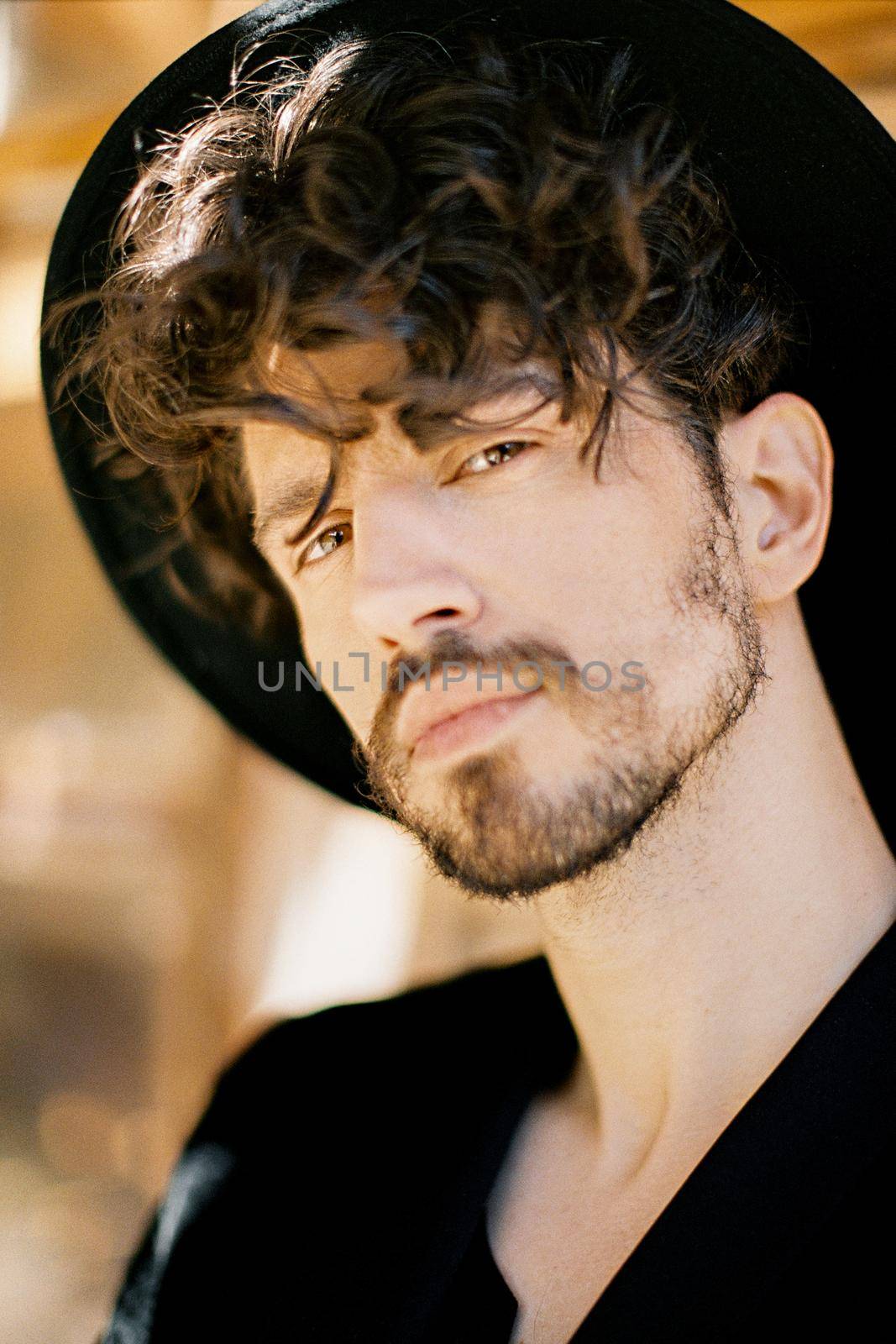 Young man in a black hat against the background of a window. Portrait. High quality photo