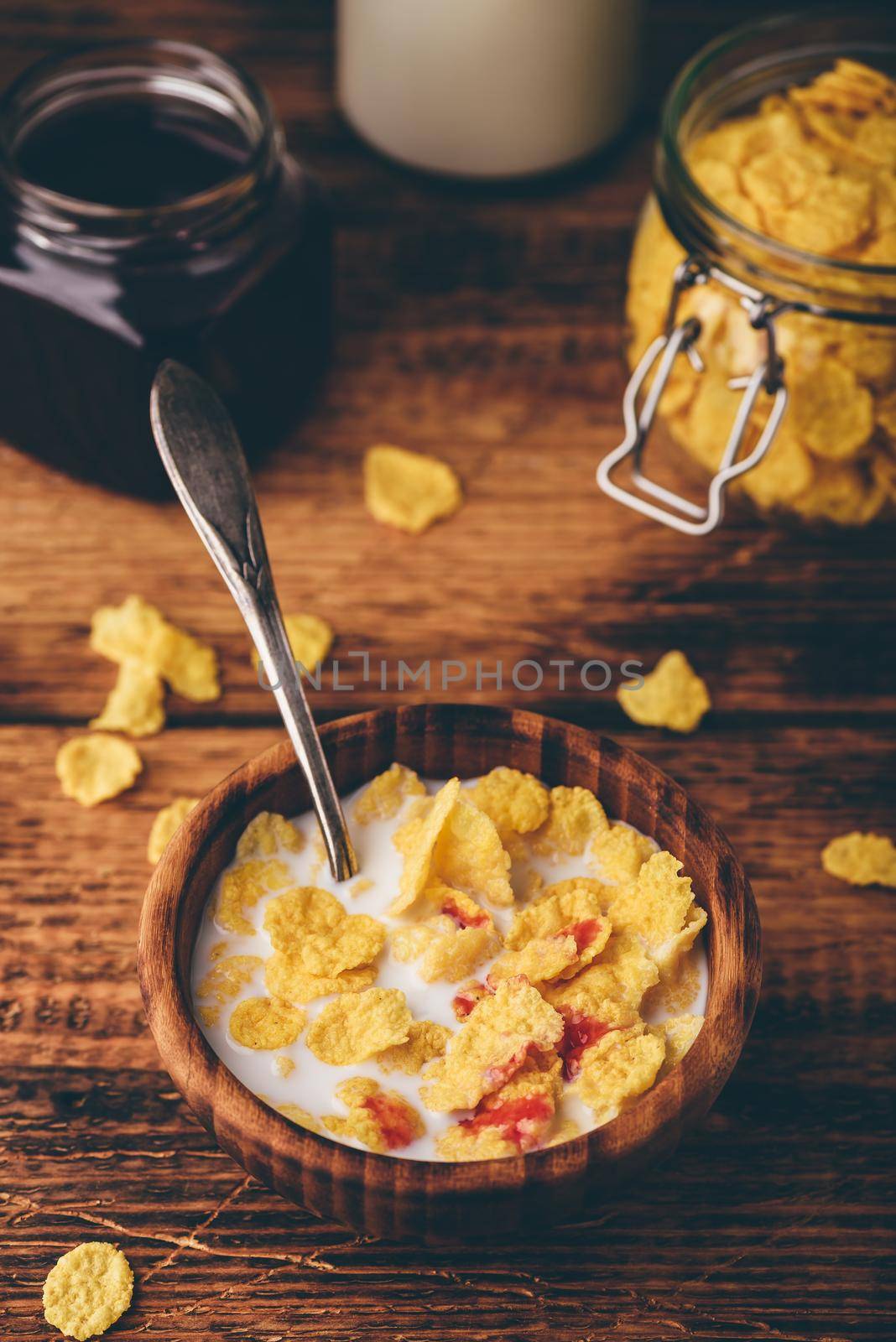 Breakfast with corn flakes, milk and berry syrup