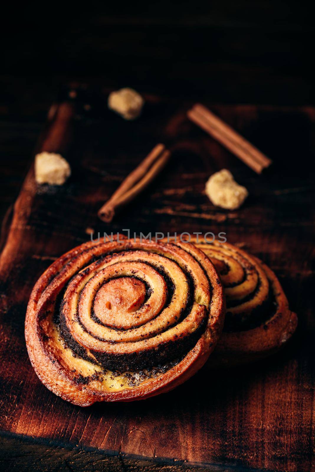 Sweet roll with poppy seeds on rustic wooden surface