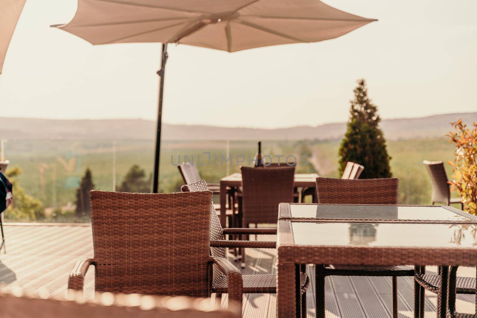 Empty tables in a street cafe overlooking mountains and trees. Sun umbrellas